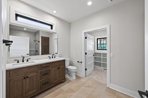 Spa-inspired primary bath featuring a dual-sink vanity, custom cabinetry, and direct access to the spacious walk-in closet.