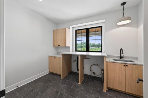 Enjoy the convenience of a spacious laundry room complete with custom cabinetry, utility sink, and folding counter.