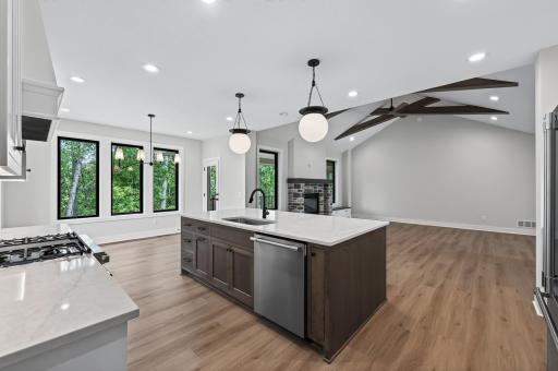 The heart of the home features a stunning open-concept design with a spacious center island, soaring ceilings, and beautiful wooded views.