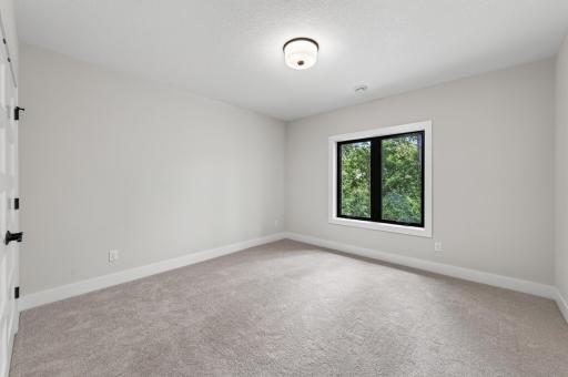 Spacious bedroom with oversized windows, soft neutral finishes, and a calming natural backdrop.