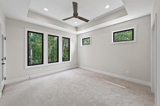 Designed for comfort and relaxation, this owner's suite offers abundant natural light and a calming wooded backdrop.
