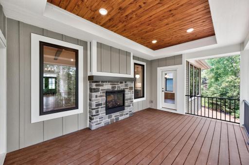 Extend your living space outdoors with this covered deck featuring a stunning see-through stone fireplace and peaceful wooded views.