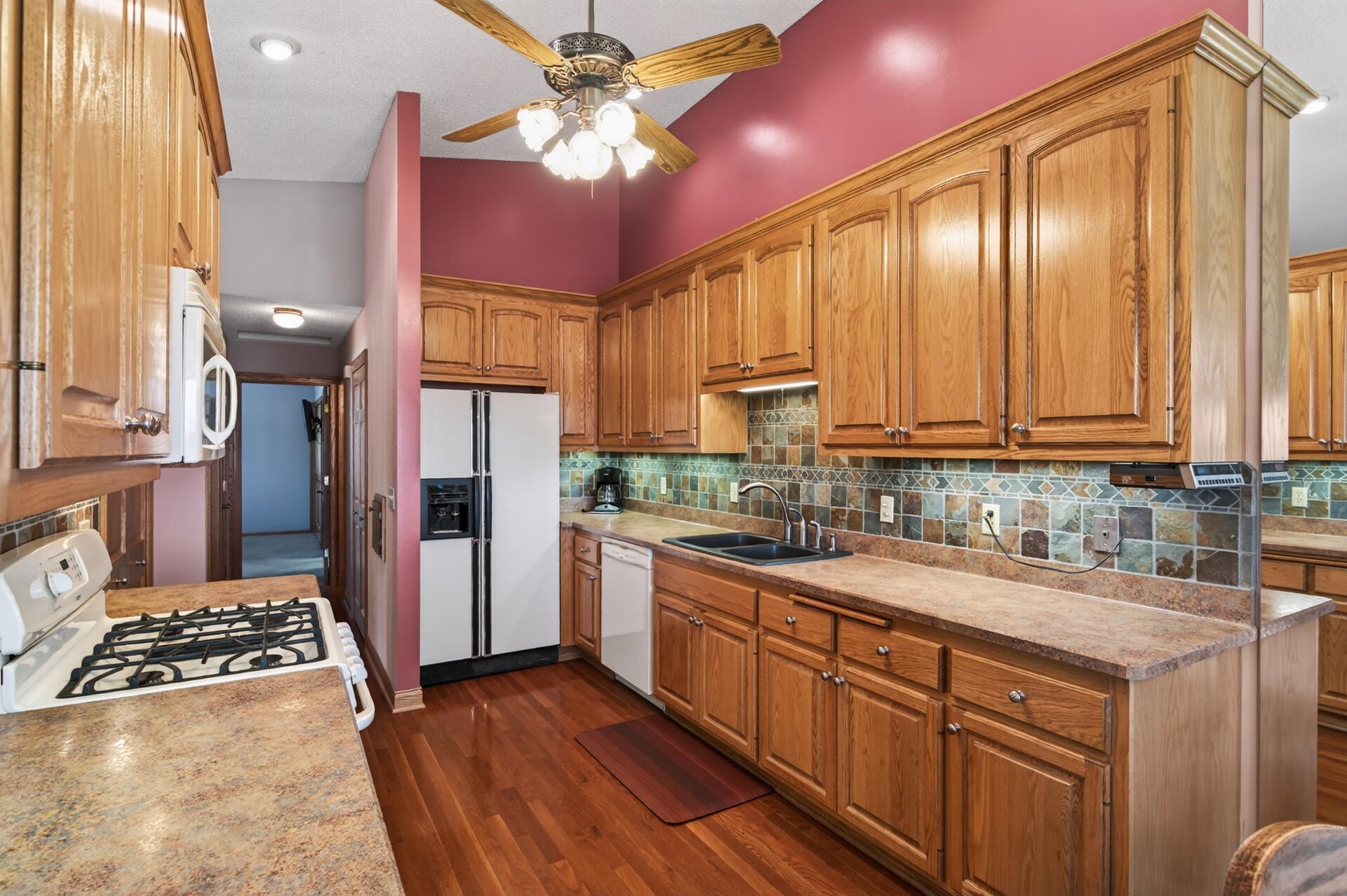 Kitchen with granite countertops, stone backsplash and gleaming hardwood floors!
