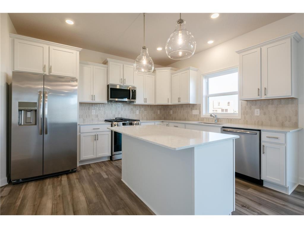 The stunning kitchen offers a large center island, quartz countertops, LVP floors, stainless appliances