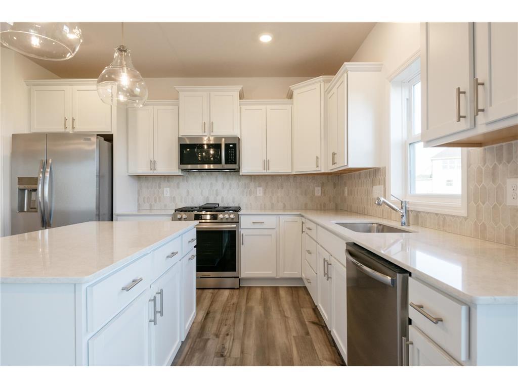 The stunning kitchen offers a large center island, quartz countertops, LVP floors, stainless appliances