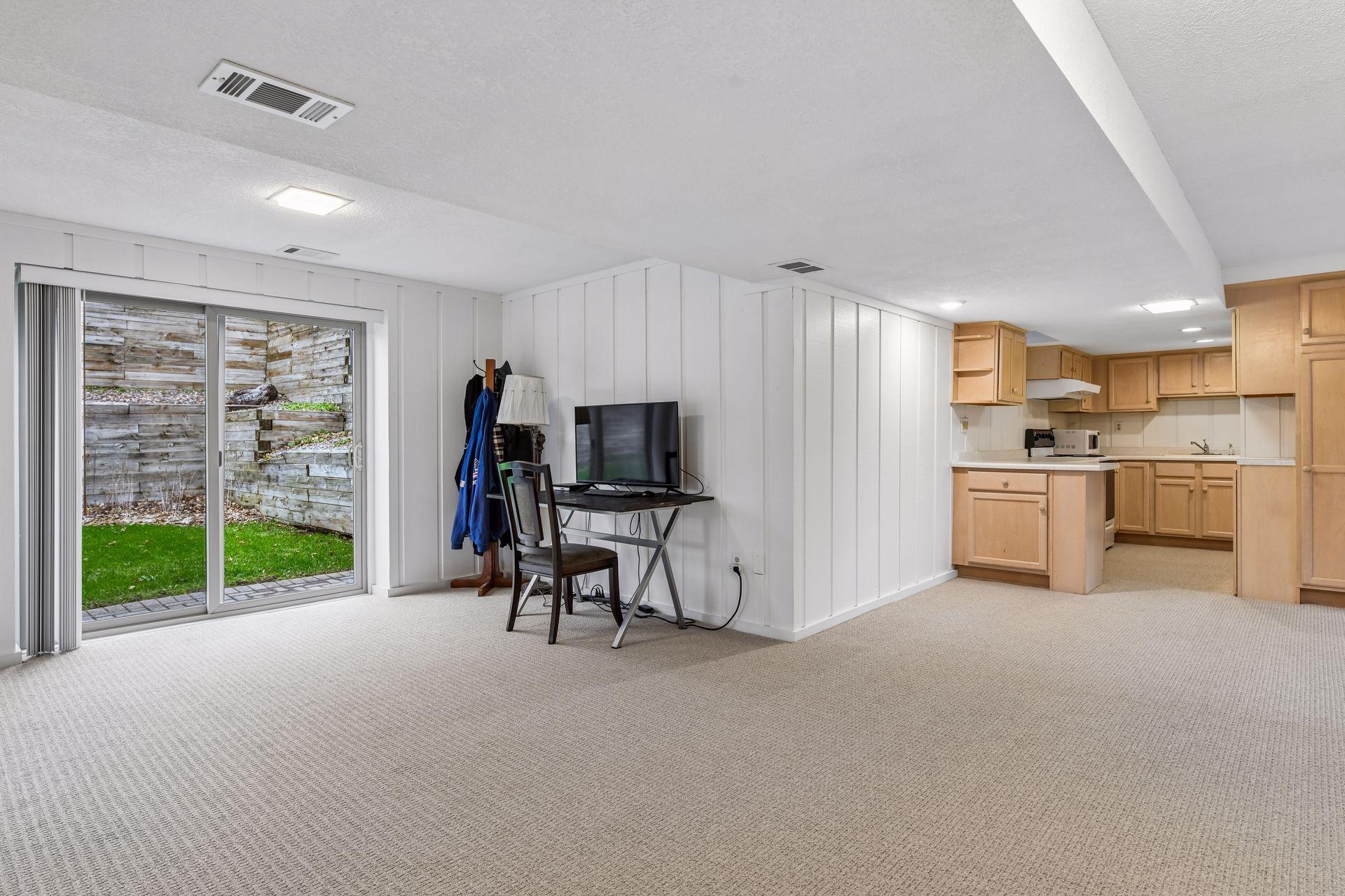 18x14 Lower-Level Flex Room with a wood-burning fireplace, new carpeting, and fresh paint. West-facing windows and walk-out doors