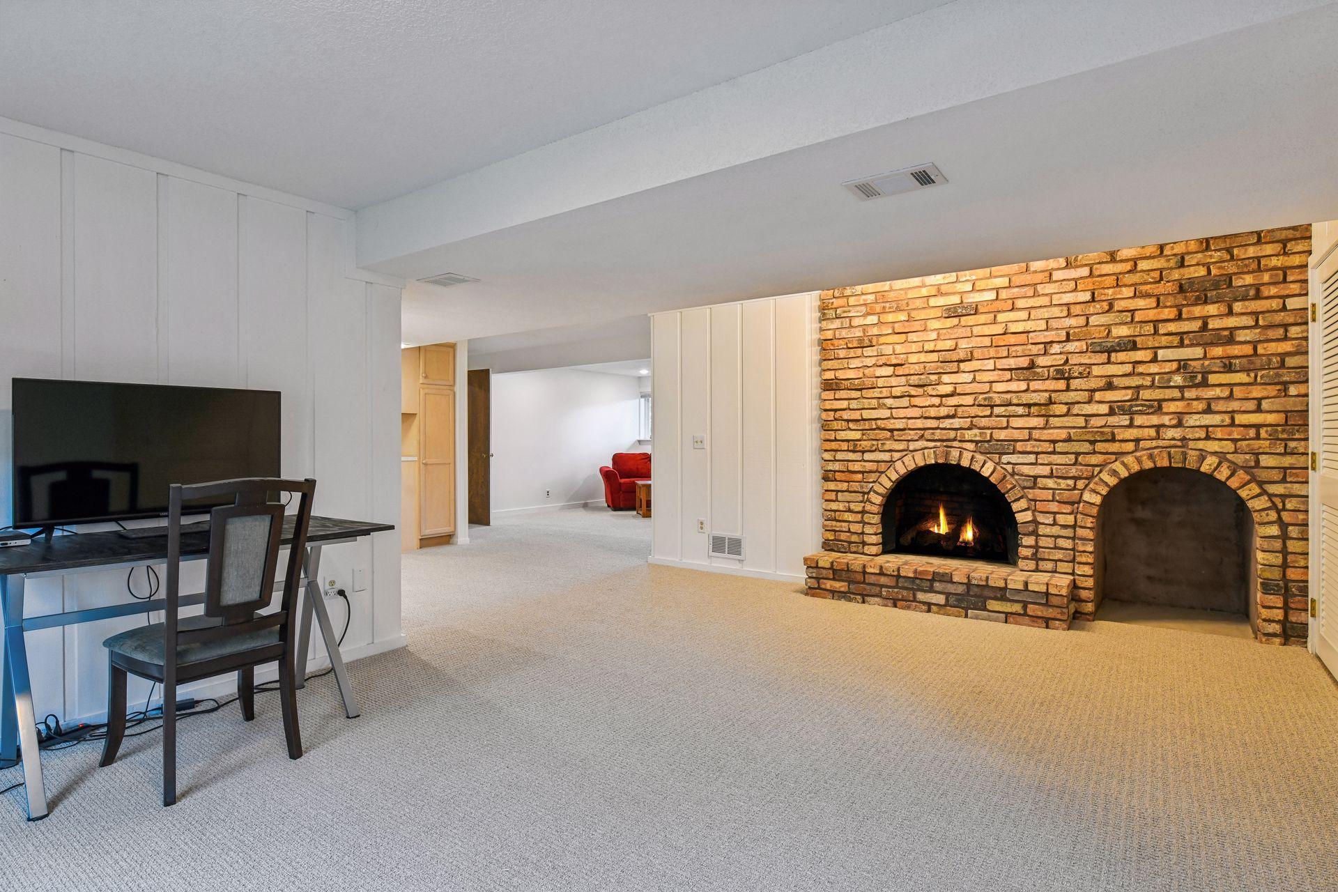 18x14 Lower-Level Flex Room with a wood-burning fireplace, new carpeting, and fresh paint. West-facing windows and walk-out doors