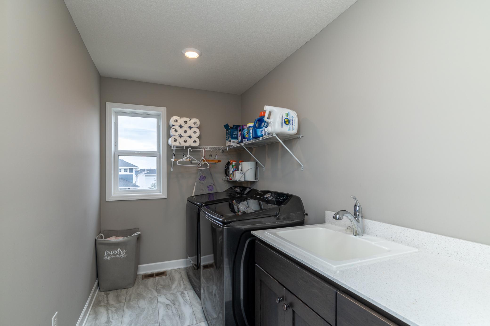 Convenient upper-level laundry room with utility sink and storage