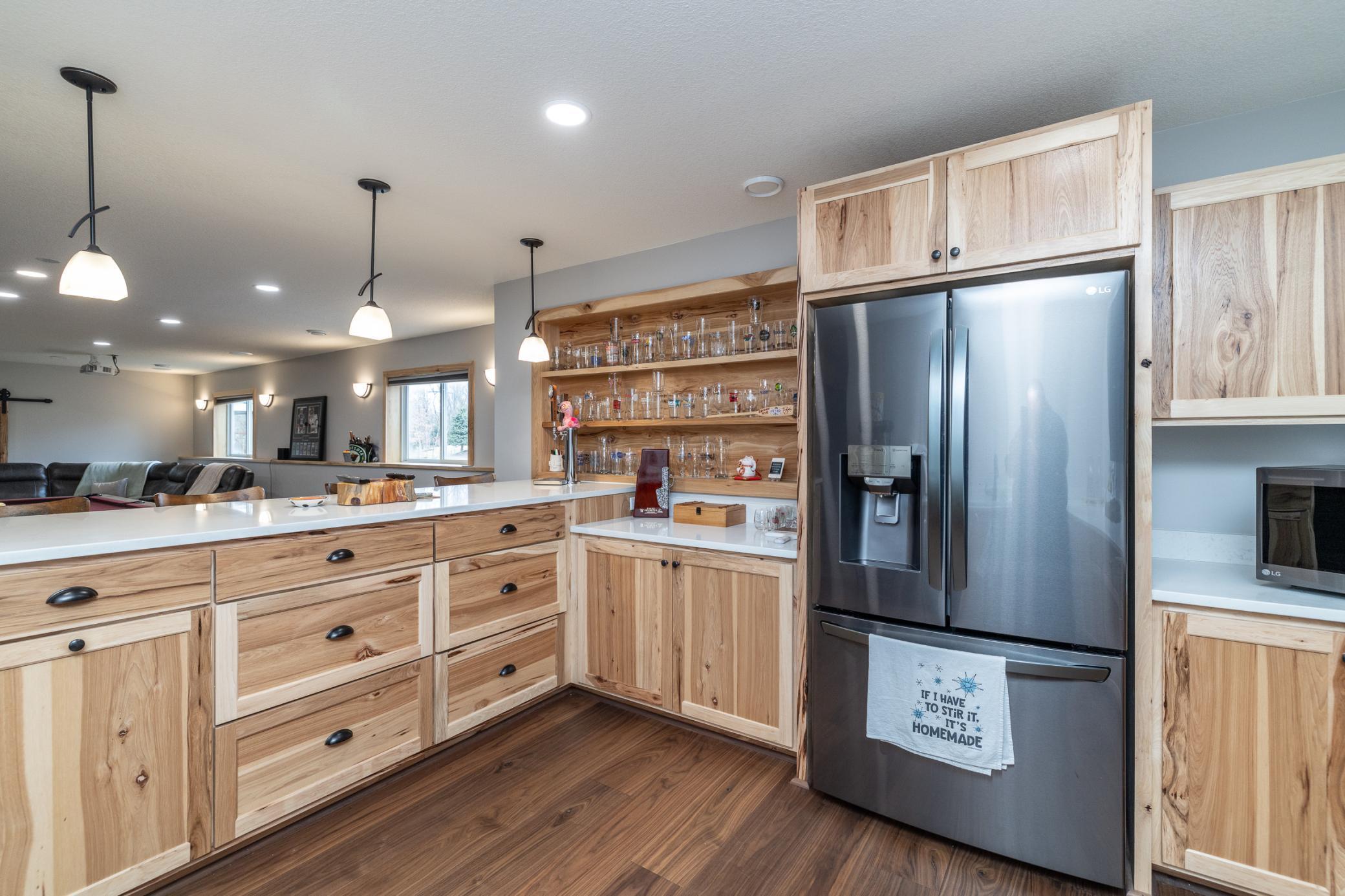 Lower-level bar with built-in shelving and stainless refrigerator