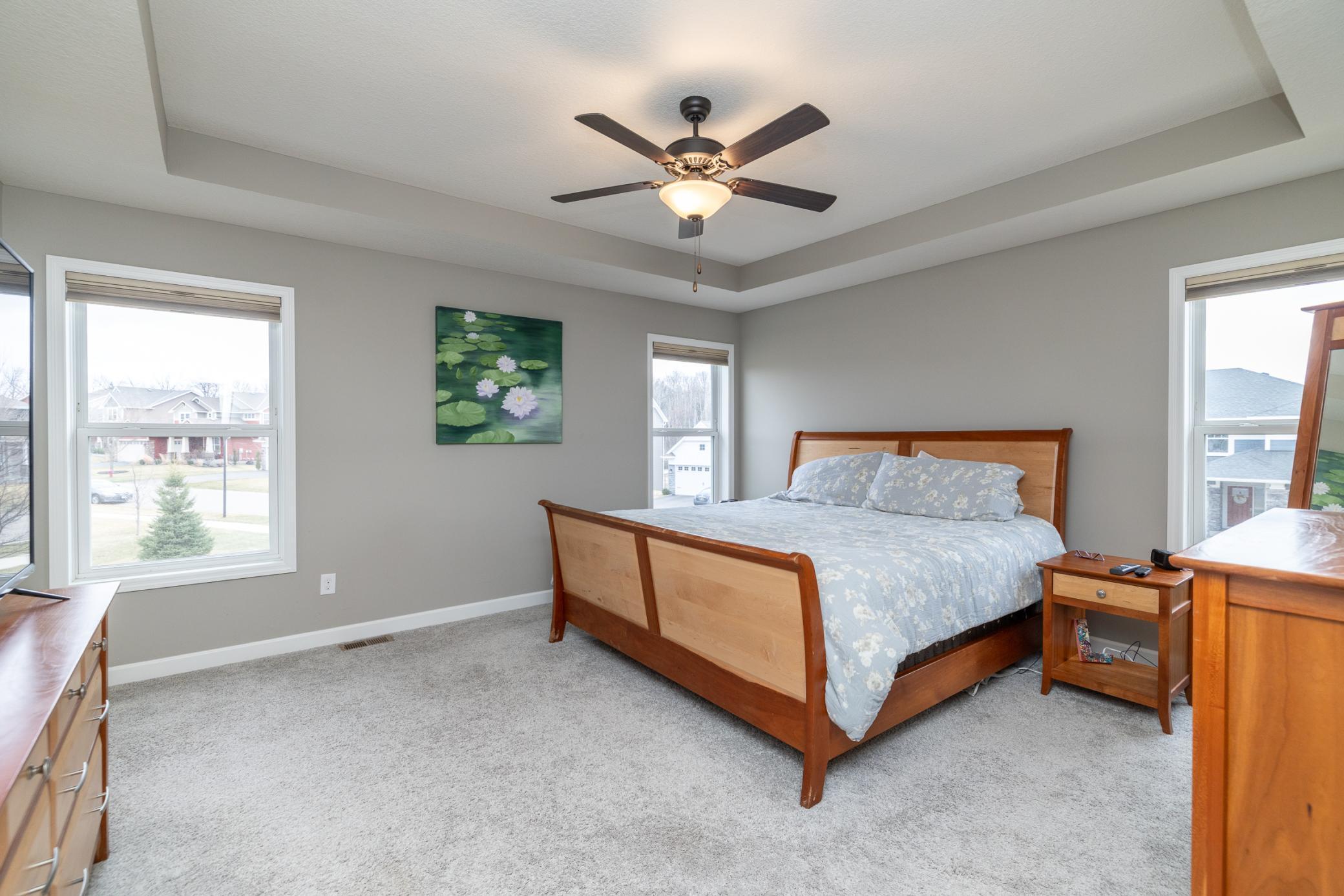 Spacious primary bedroom with tray ceiling and abundant natural light