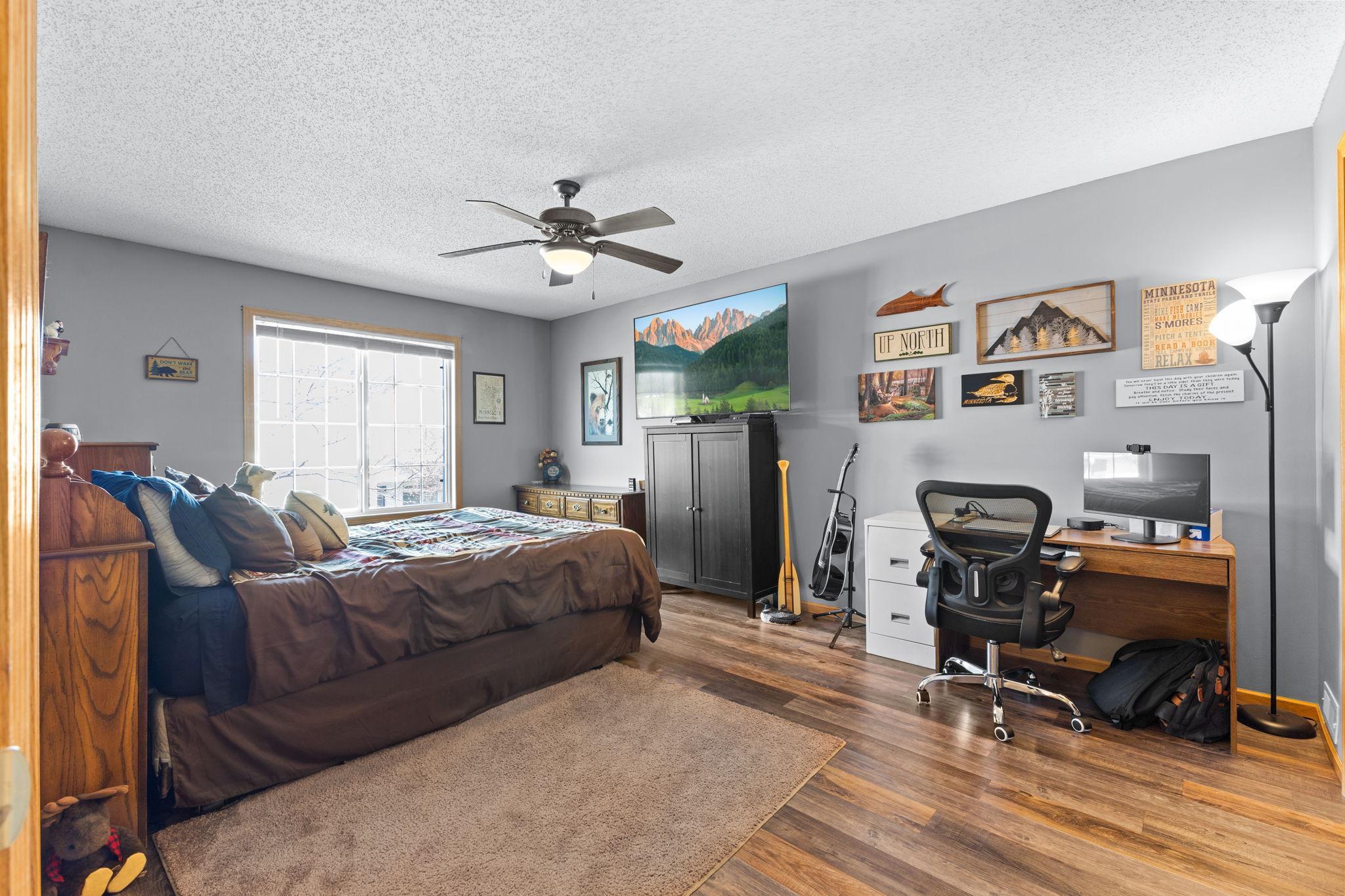 Spacious primary bedroom with large window and room for seating or workspace