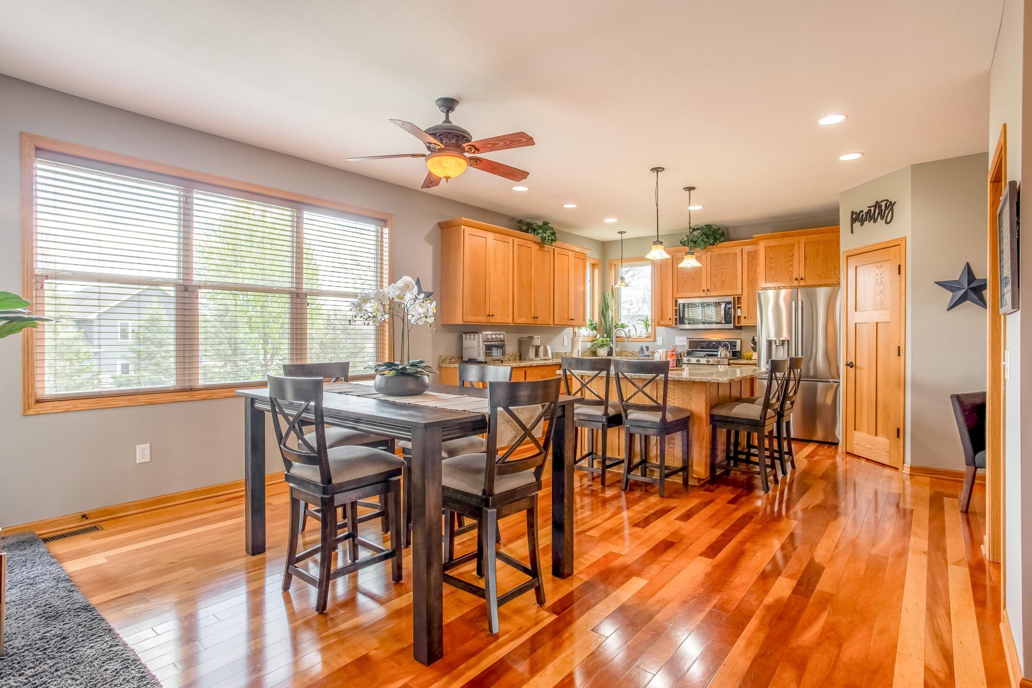 Bright and open dining area with rich hardwood floors, oversized windows, and seamless flow into the gourmet kitchen.