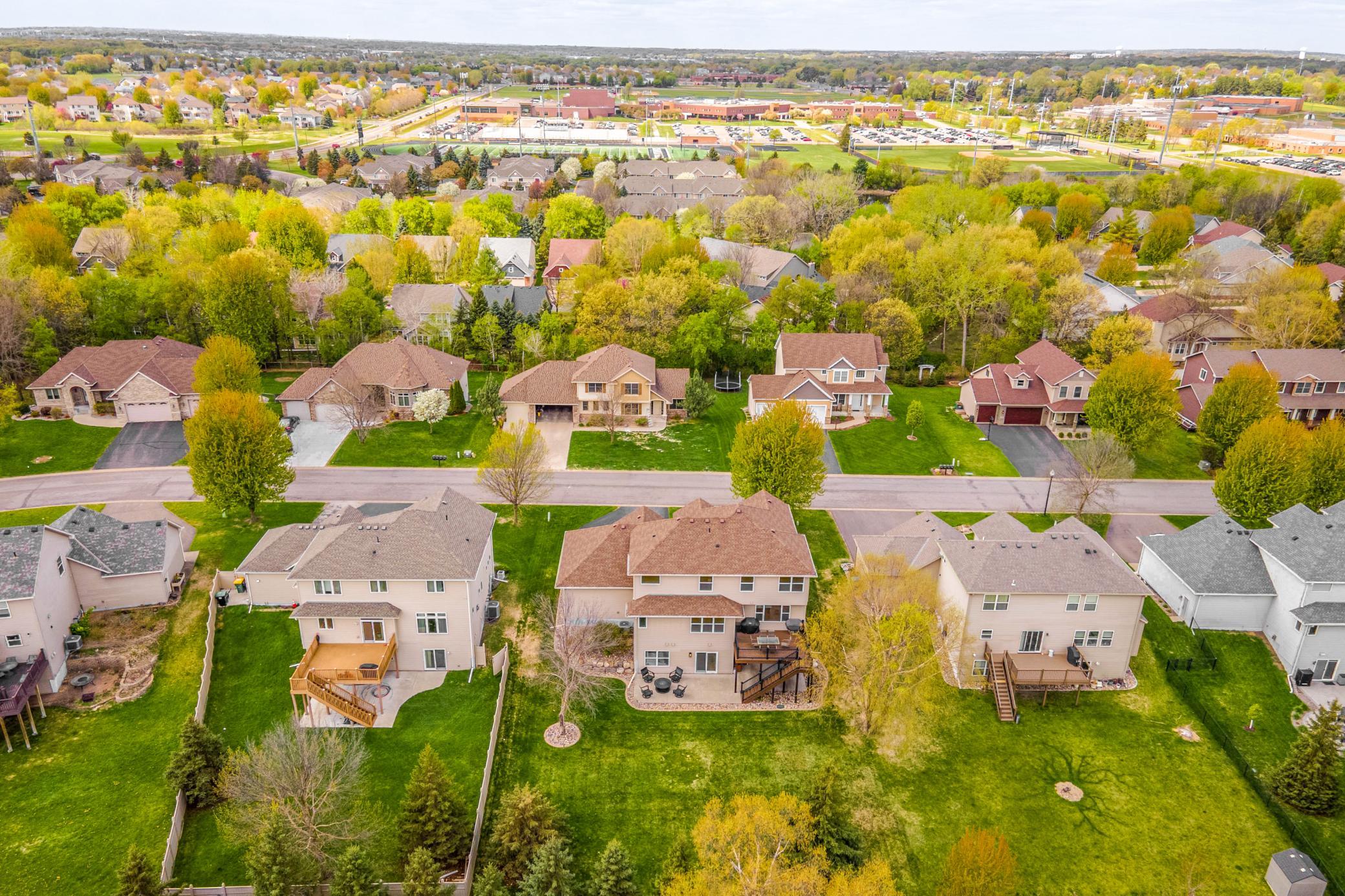 Aerial view showcasing the home’s spacious lot, mature trees, and convenient location within a beautiful established neighborhood minutes from Champlin Park High School.