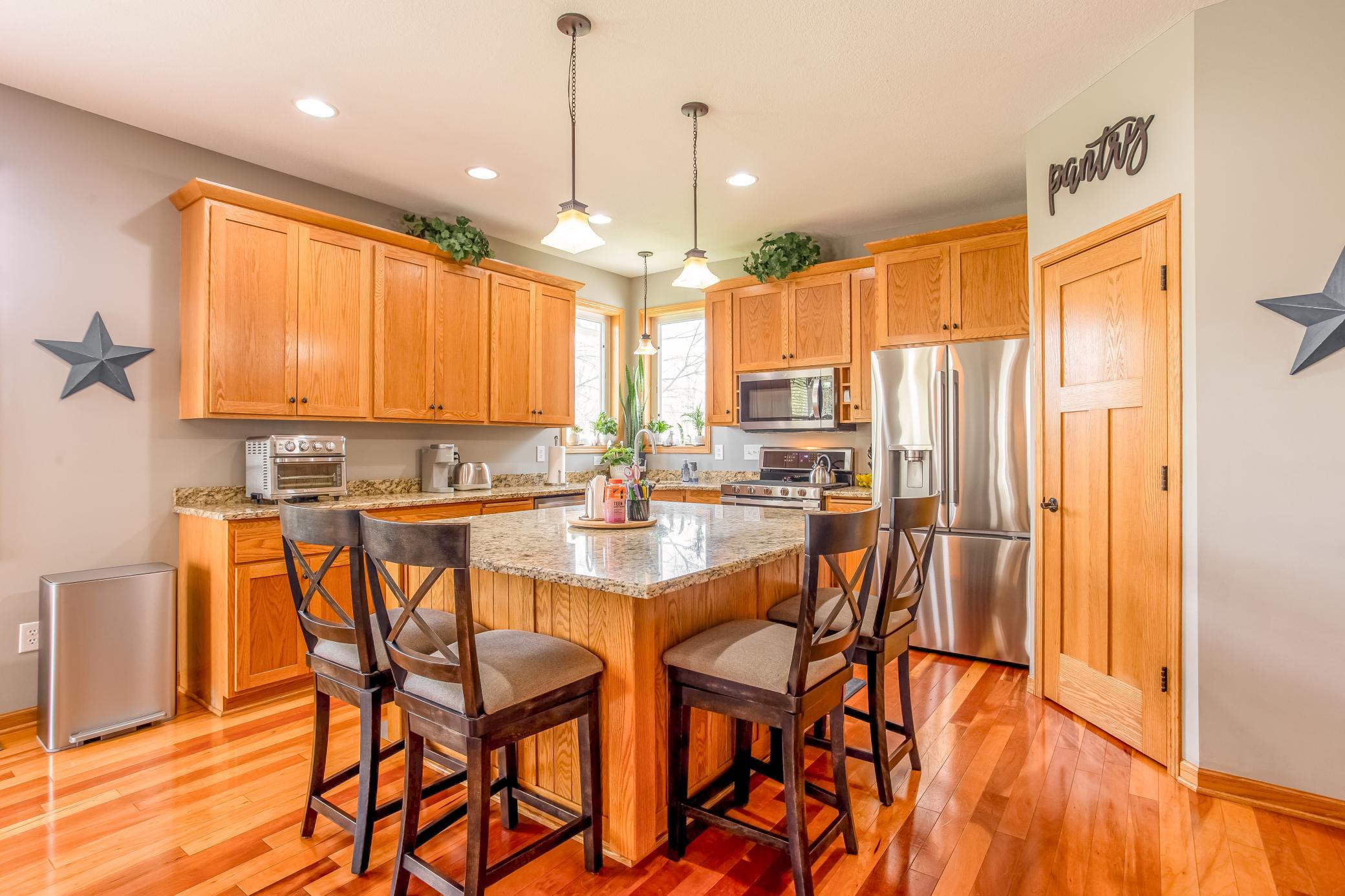 Well-appointed kitchen featuring granite countertops, stainless-steel appliances, abundant cabinetry, and a large center island with seating.