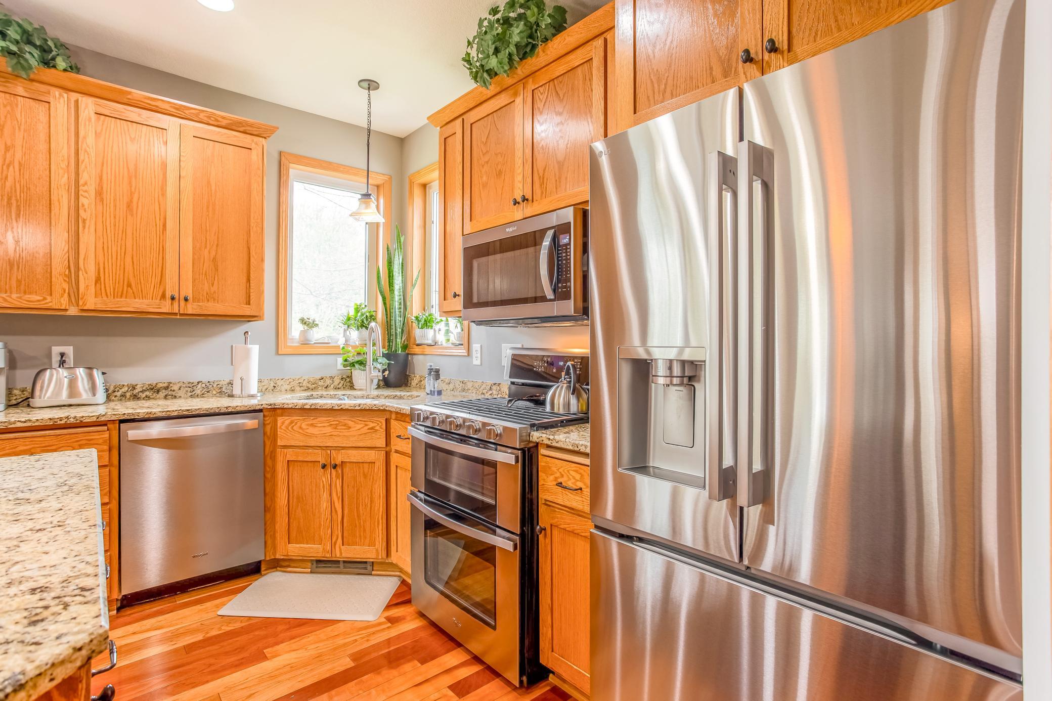 Stylish kitchen with stainless-steel appliances, granite surfaces, and beautiful natural light from corner windows above the sink.