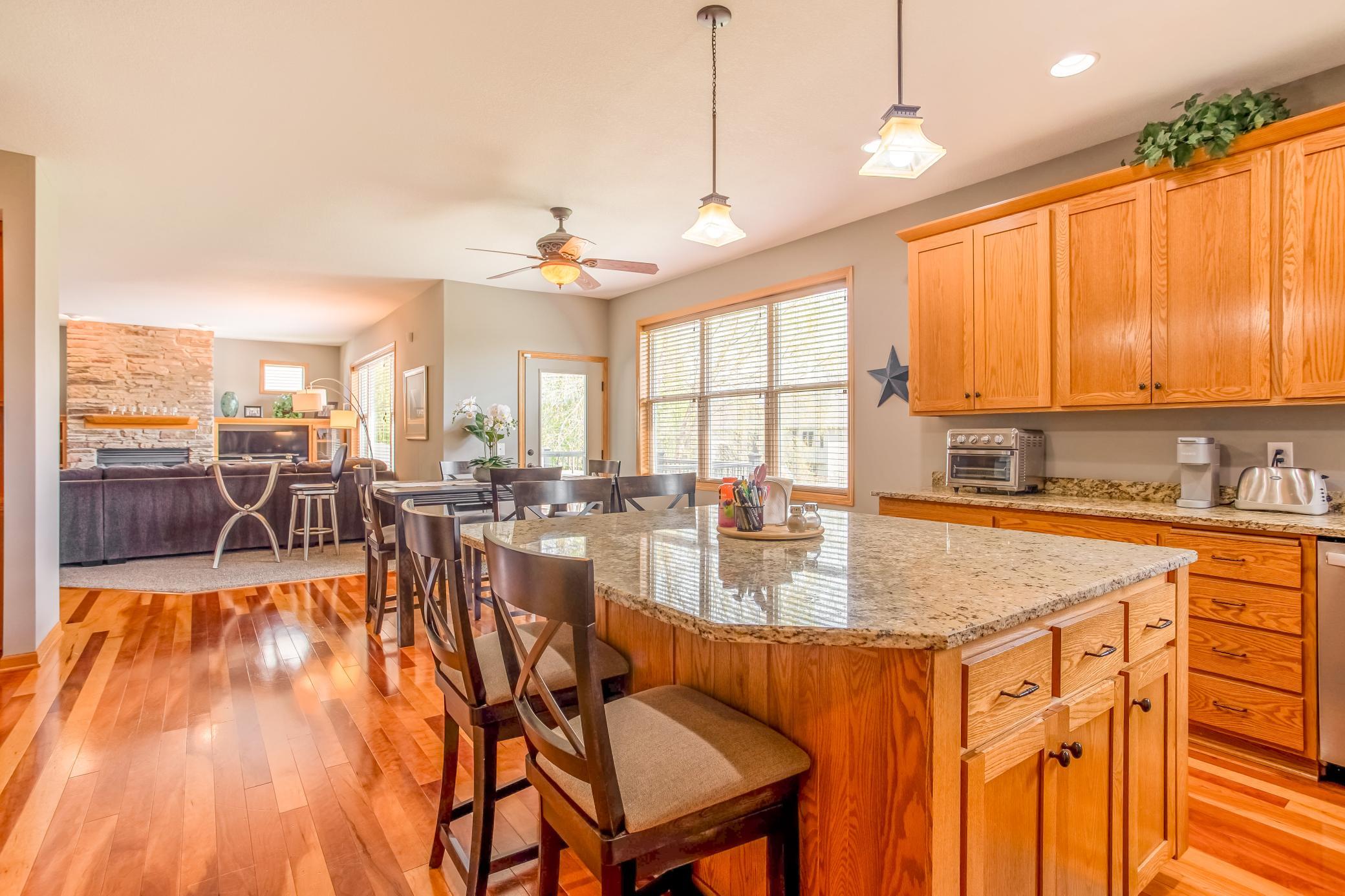 Spacious open-concept layout with a large center island, hardwood flooring, and sightlines into the inviting living room.