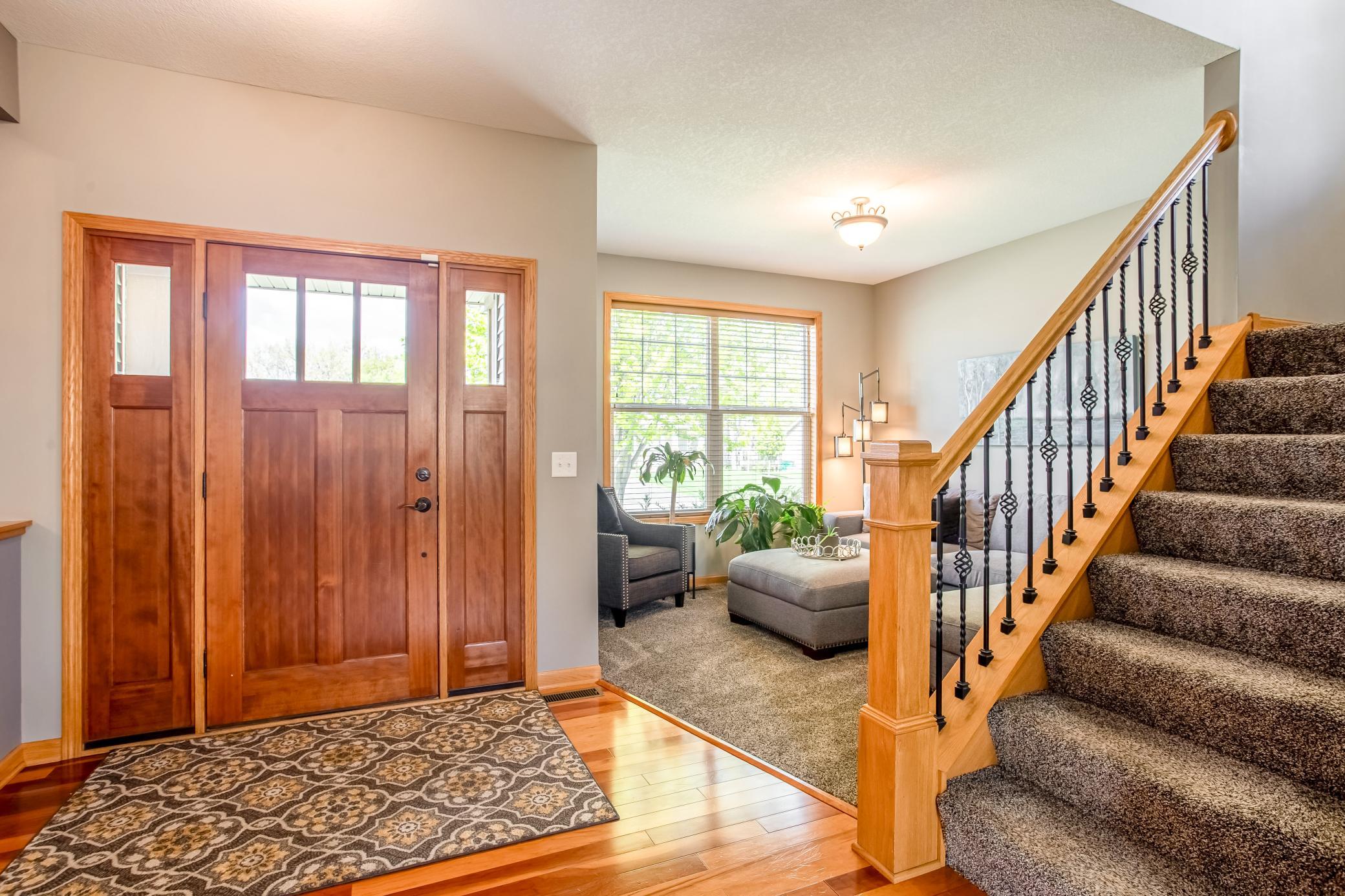 Inviting front entry with warm wood accents, soaring ceilings, and a cozy sitting area just beyond the foyer.