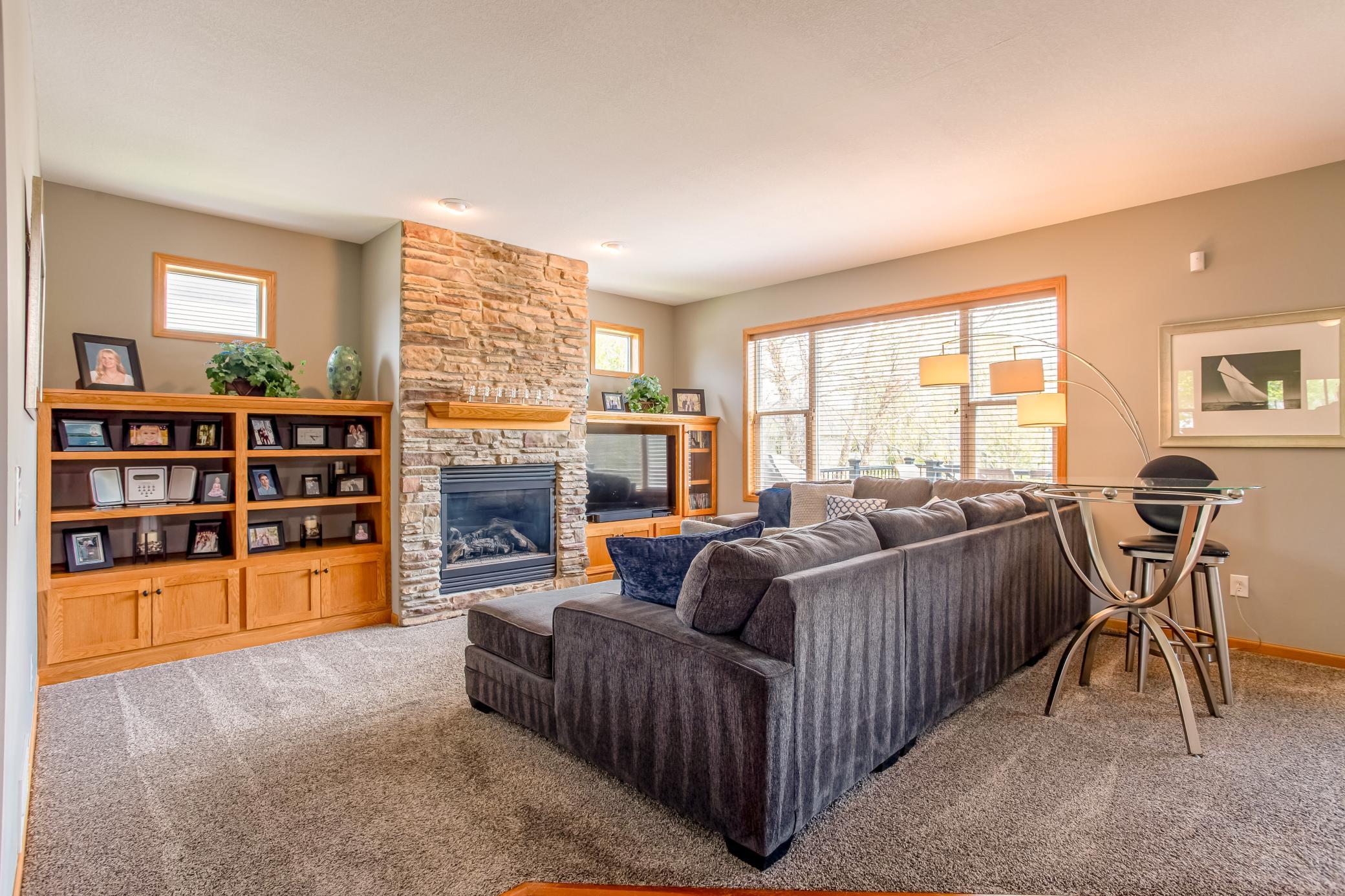 Cozy living room centered around a stunning floor-to-ceiling stone fireplace with custom built-ins and large backyard-facing windows.