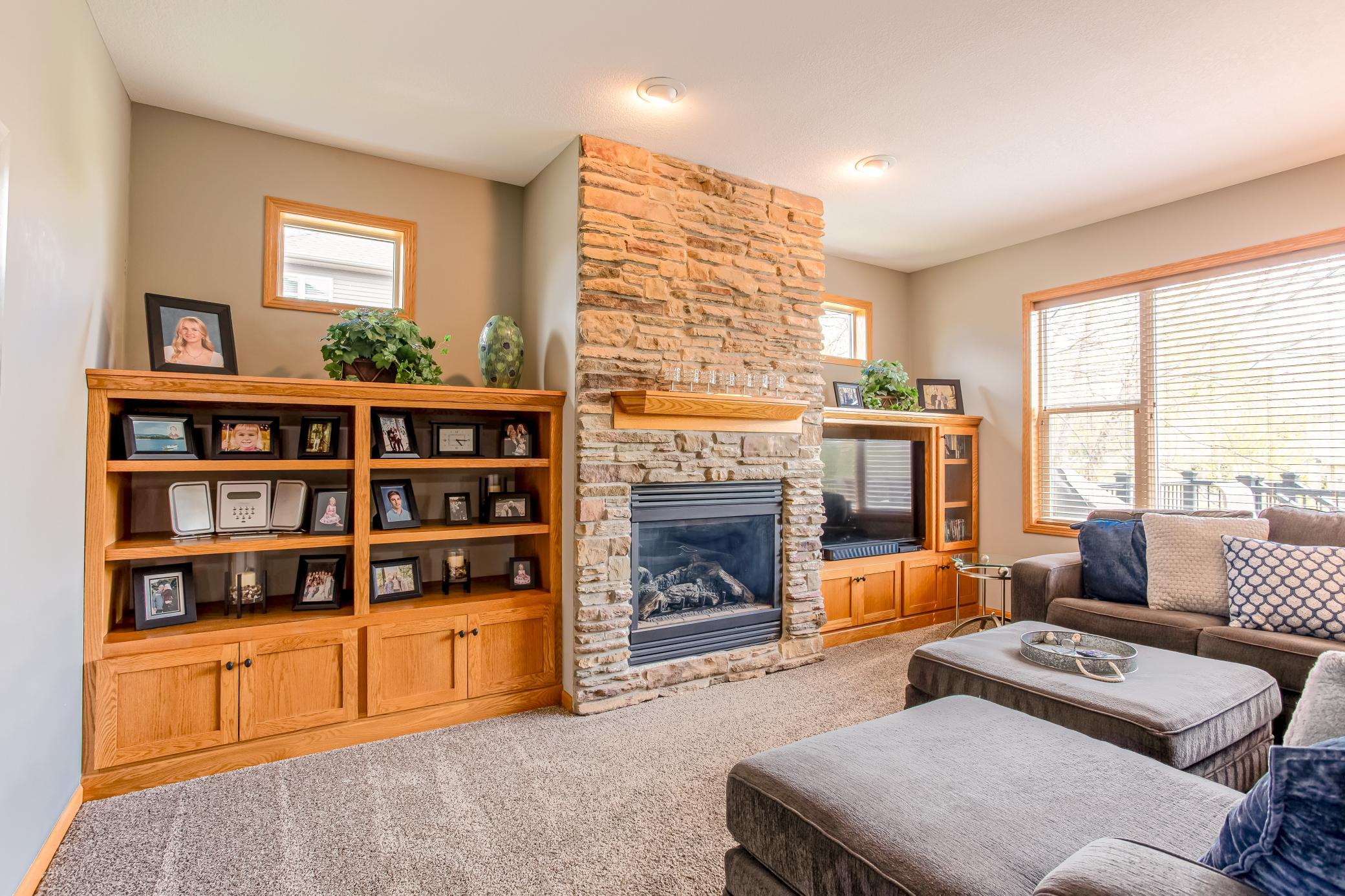 Warm and welcoming living room featuring custom cabinetry, a beautiful gas fireplace, and abundant natural light.