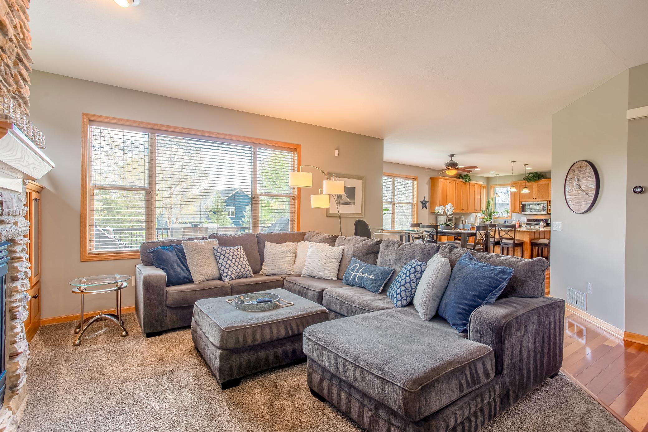 Spacious and comfortable living room with oversized windows, plush seating, and open sightlines to the kitchen and dining areas.