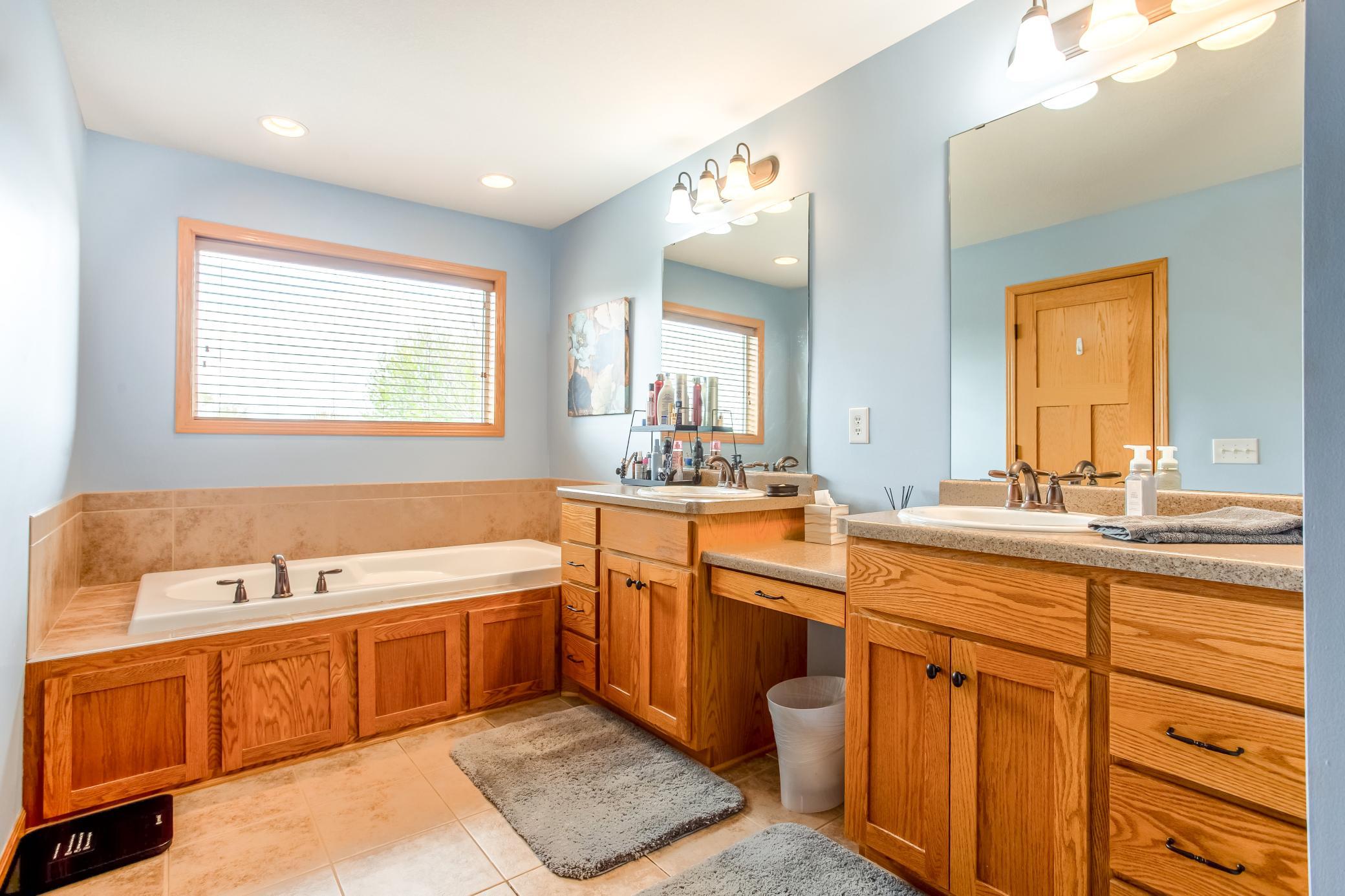 Spa-inspired primary bathroom with dual vanities, jetted tub, and abundant natural light.