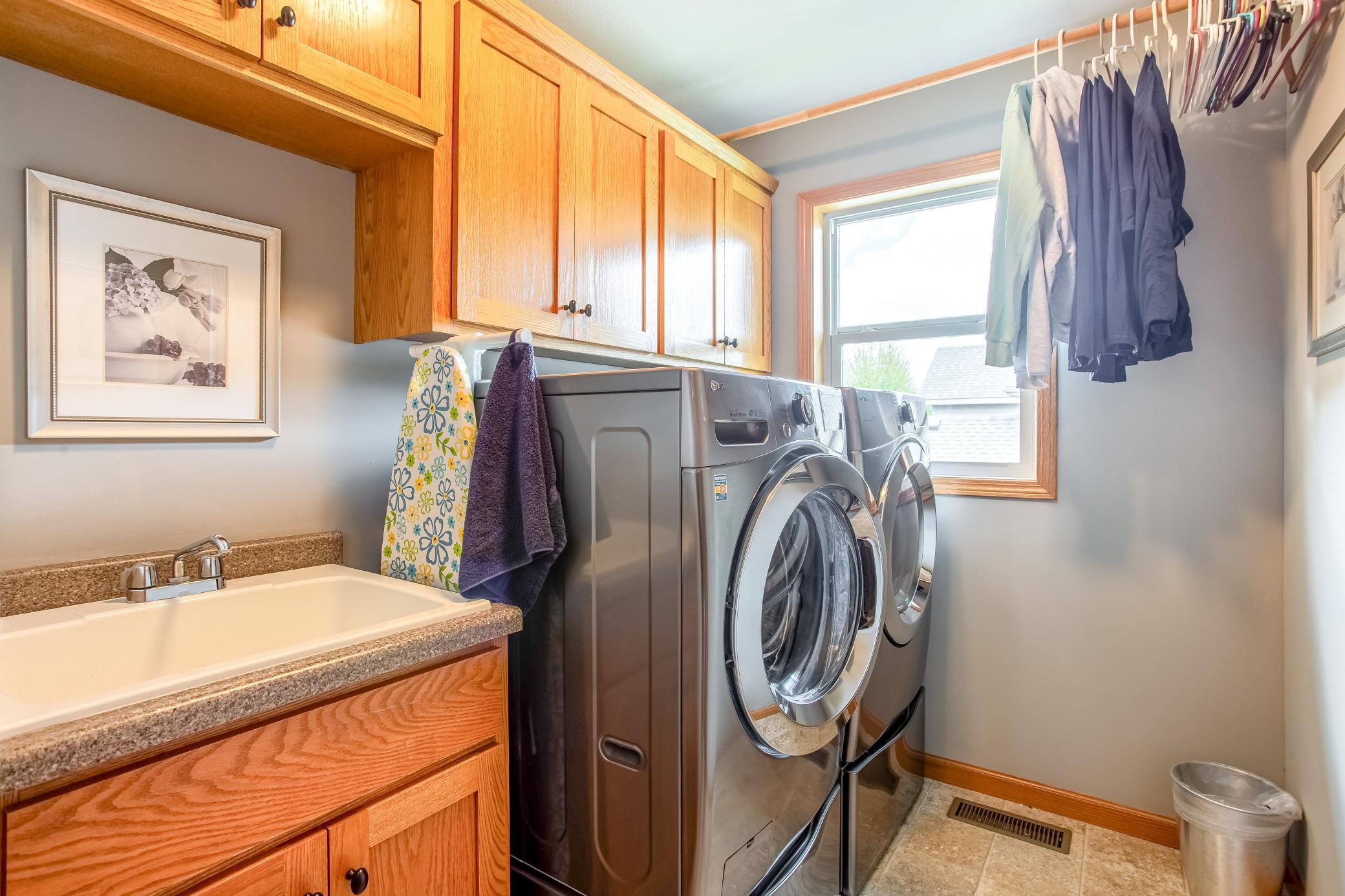 Upper-level laundry room with built-in cabinetry, utility sink, and full-size washer and dryer for everyday convenience.