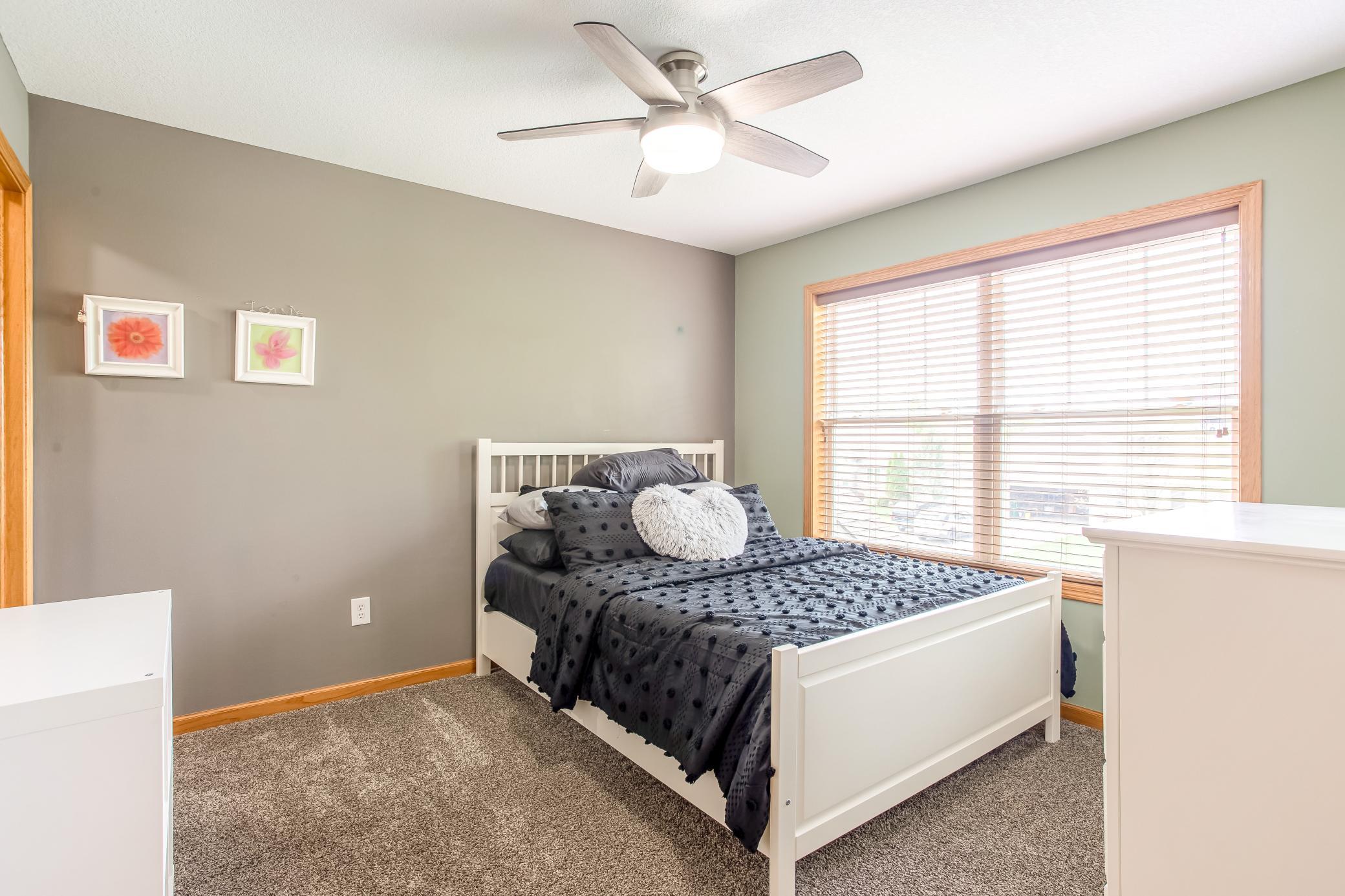 Bright and inviting bedroom with large windows, updated ceiling fan, and soft natural light throughout.