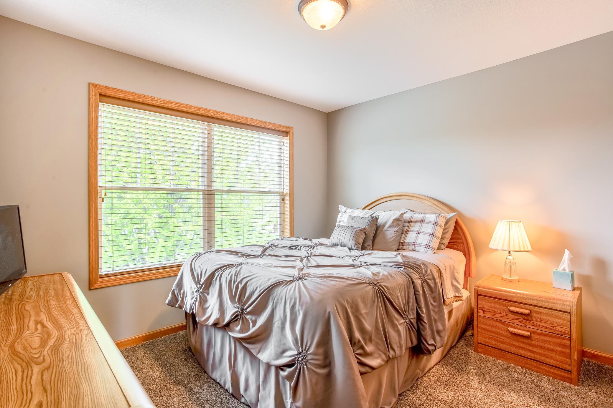 Charming bedroom with oversized windows, warm natural light, and a relaxing atmosphere.