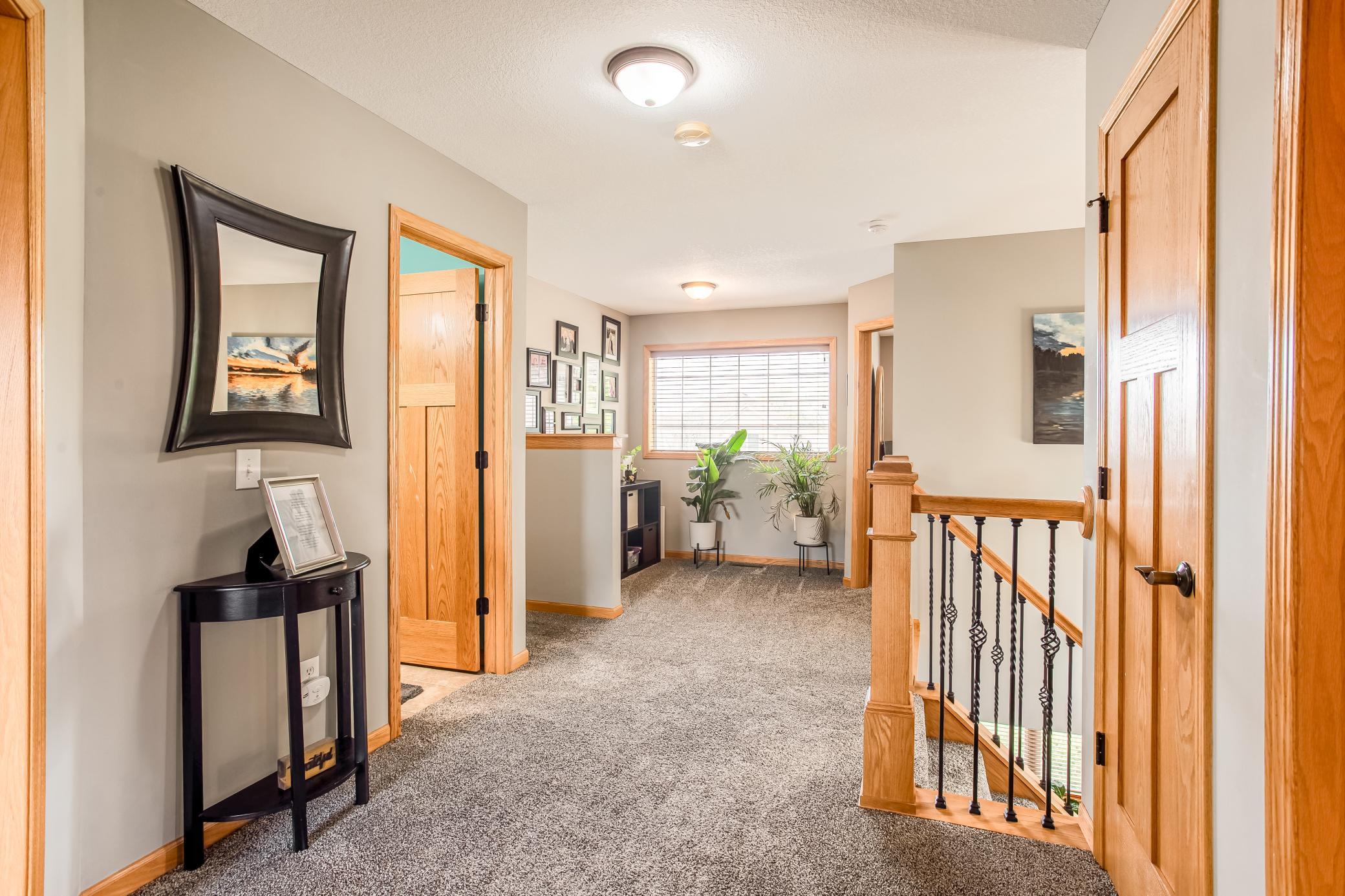 Bright upper-level landing featuring warm woodwork, open sightlines, and a welcoming layout connecting the bedrooms.