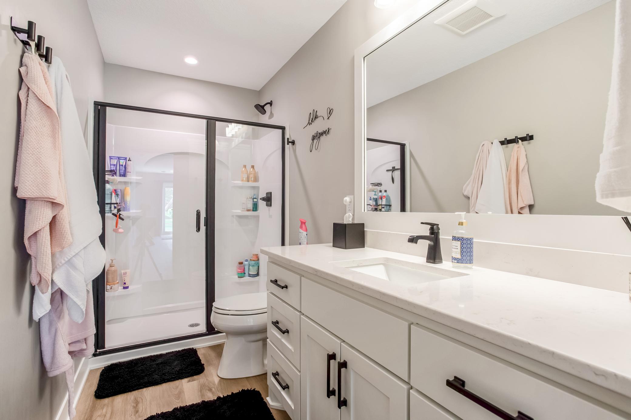 Stylish lower-level bathroom featuring a modern vanity, quartz countertops, sleek black fixtures, and a beautifully finished walk-in shower.