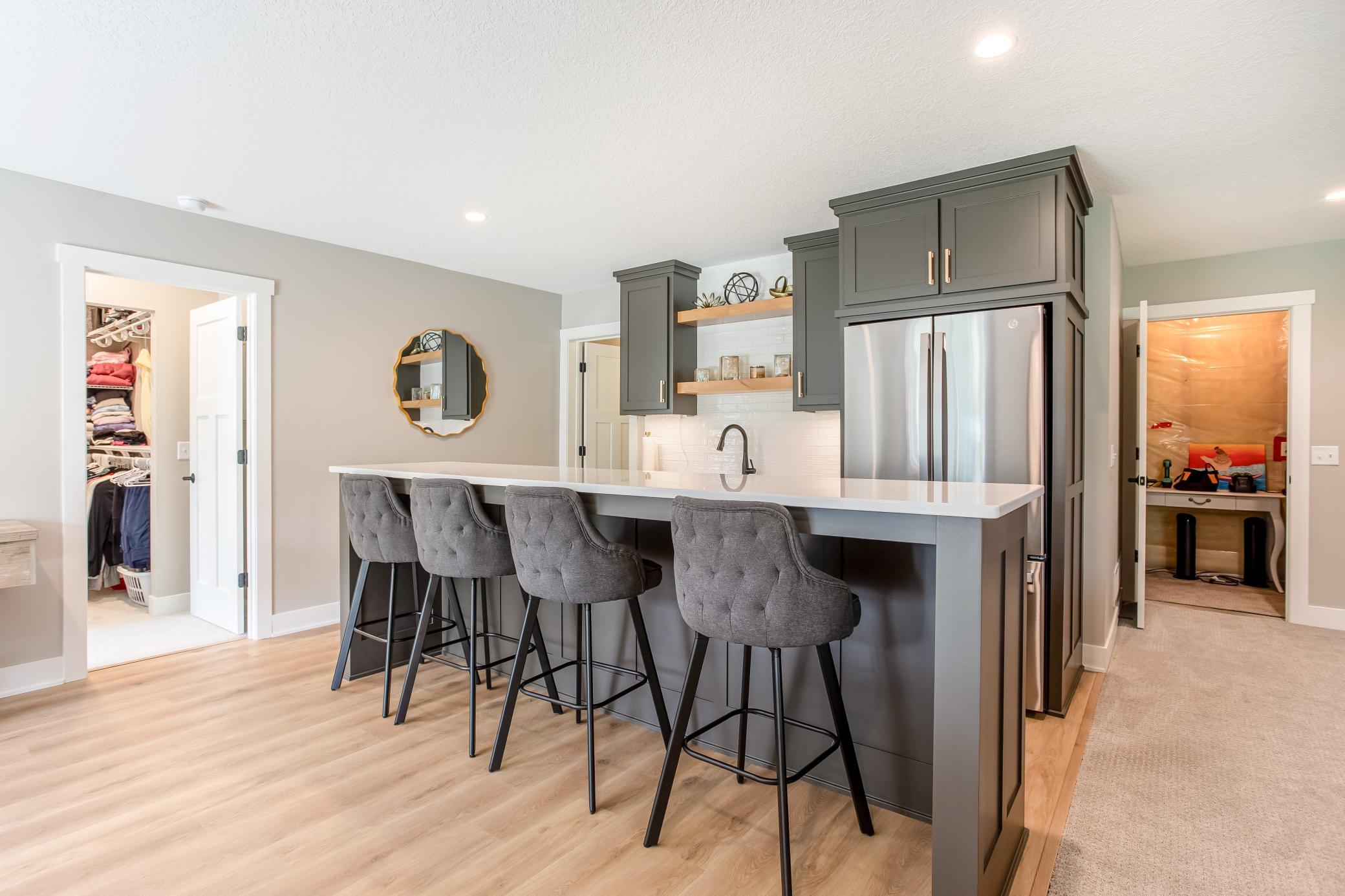 Impressive lower-level wet bar with quartz countertops, custom cabinetry, open shelving, and seating for casual gatherings.