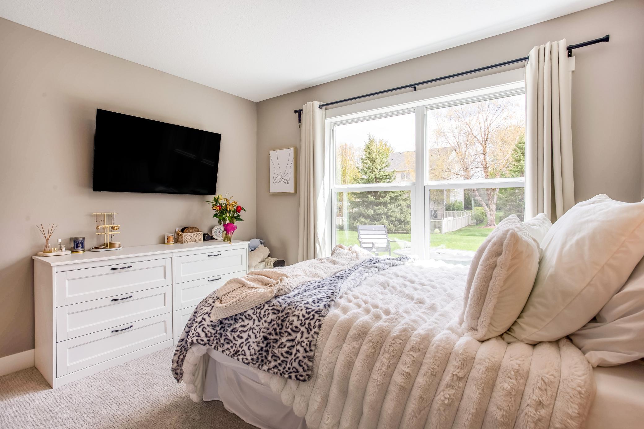 Inviting guest bedroom featuring abundant natural light, plush carpeting, and a warm, relaxing atmosphere.