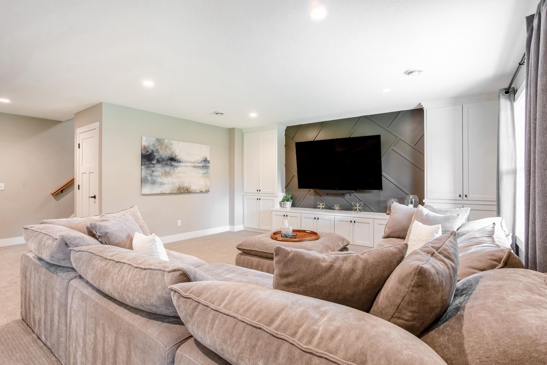 Stylish and comfortable gathering space with recessed lighting, custom cabinetry, and a beautifully designed media wall.