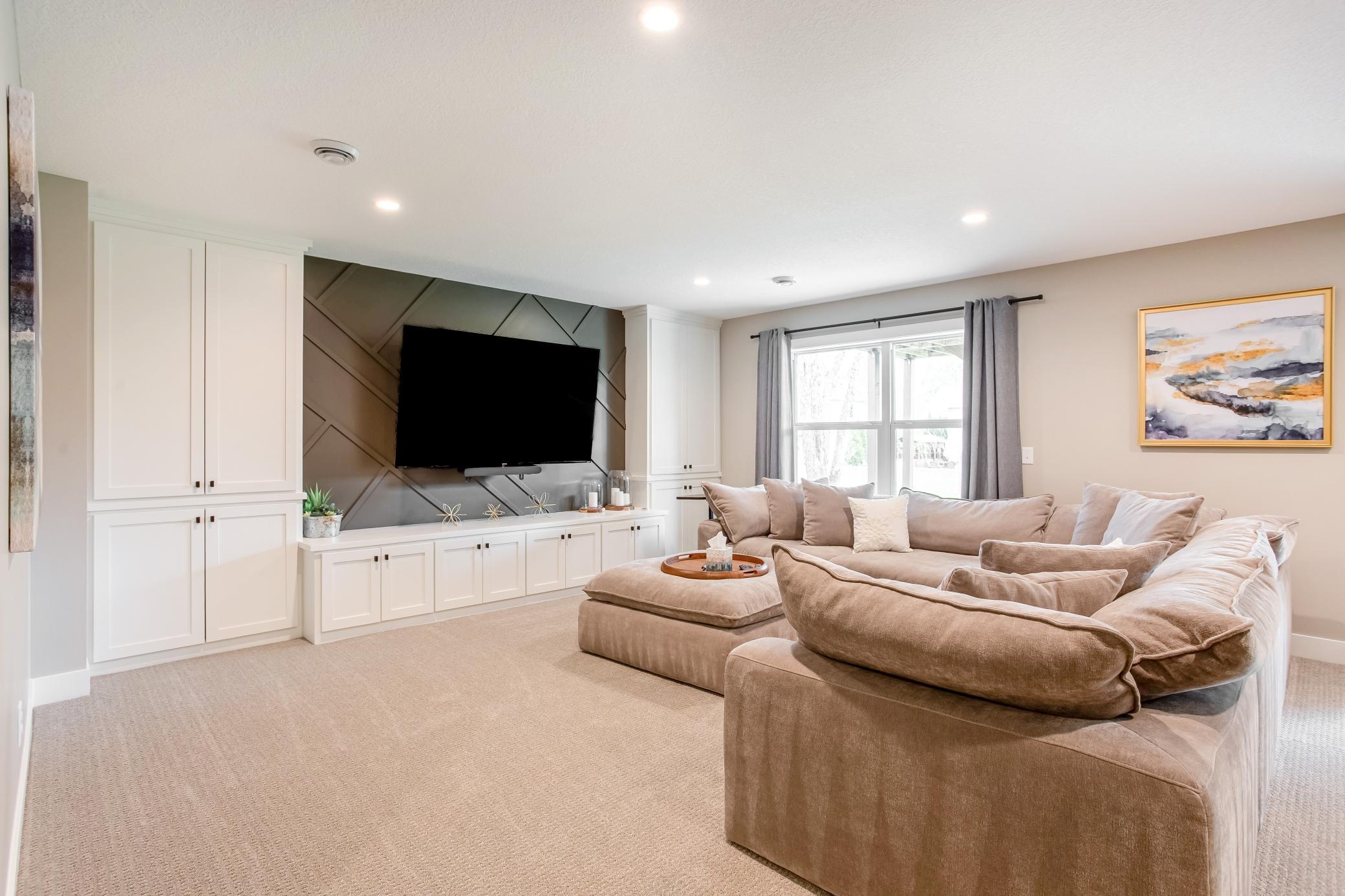 Expansive lower-level family room featuring custom built-ins, designer accent wall, and plenty of space for relaxing or entertaining.