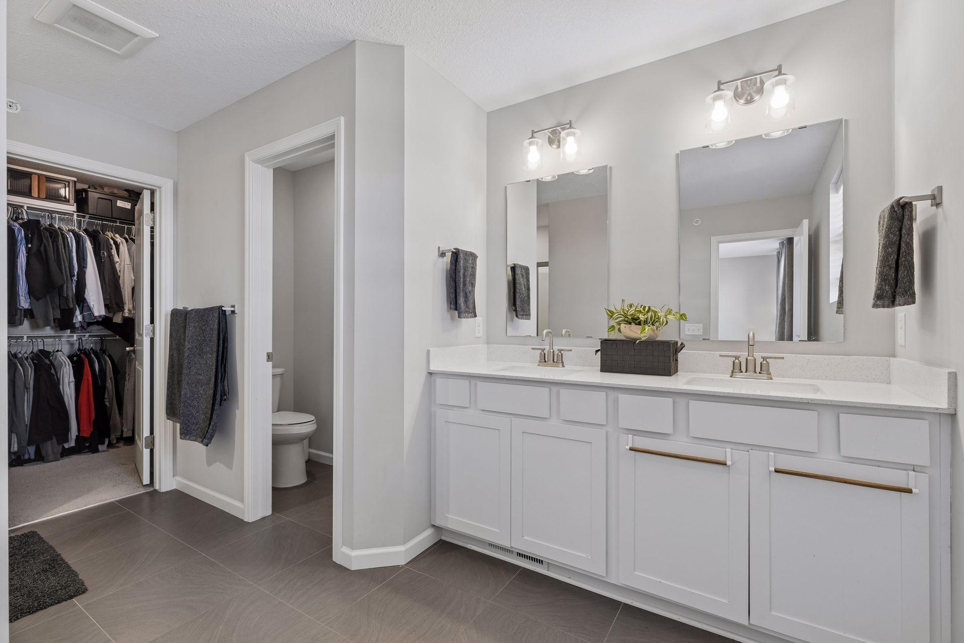 Primary bathroom featuring double sinks and separate toilet area for added functionality.