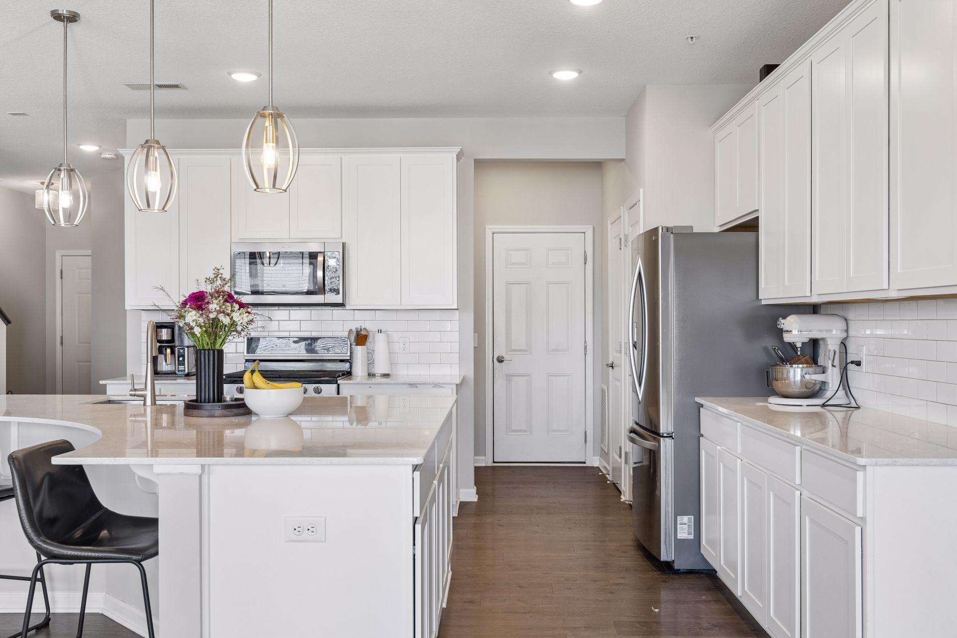 Kitchen with refrigerator, extended island workspace, and open sightlines to living areas.