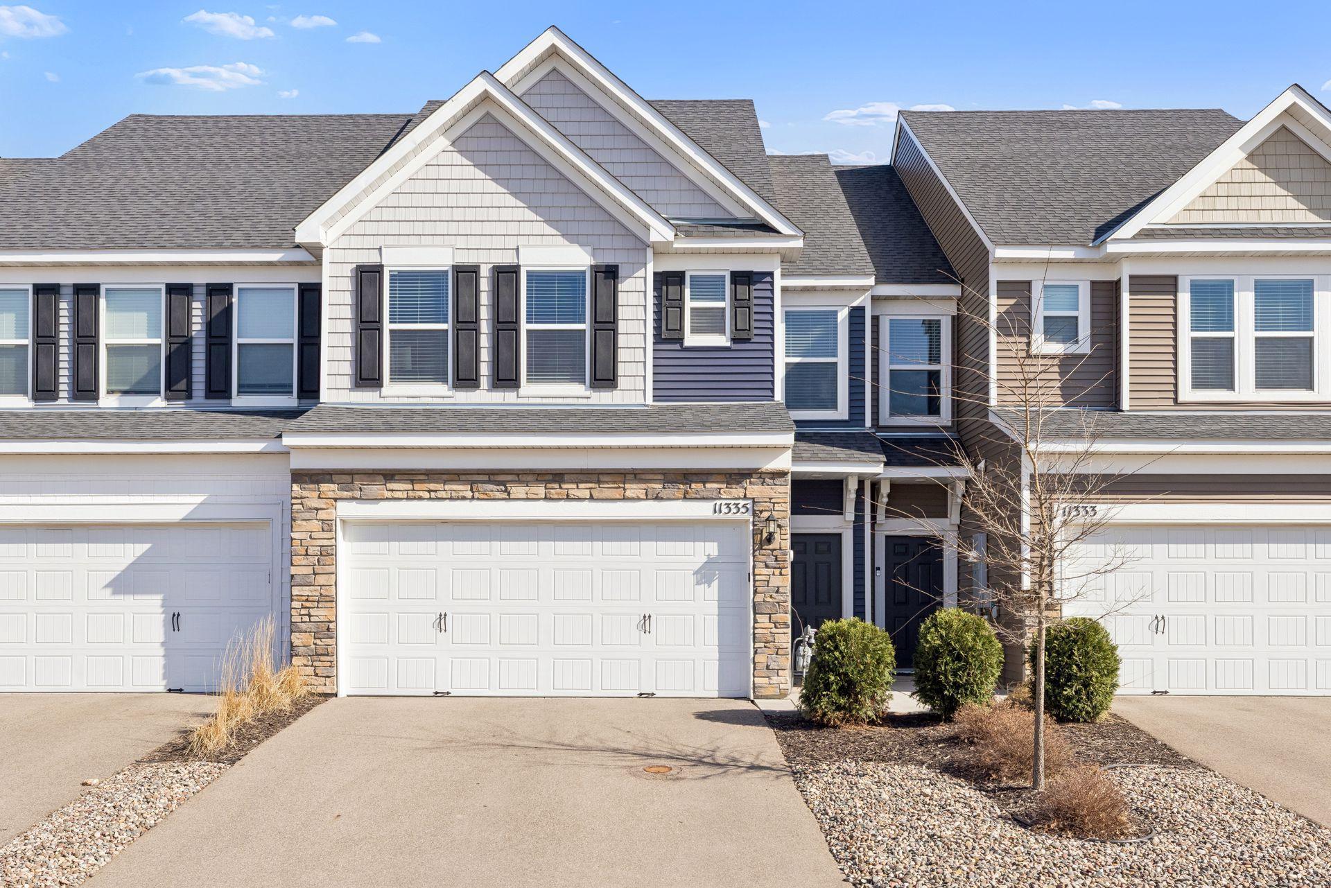 Front exterior of this townhouse featuring blue and gray siding, white trim, and stone-accented garage for added curb appeal.