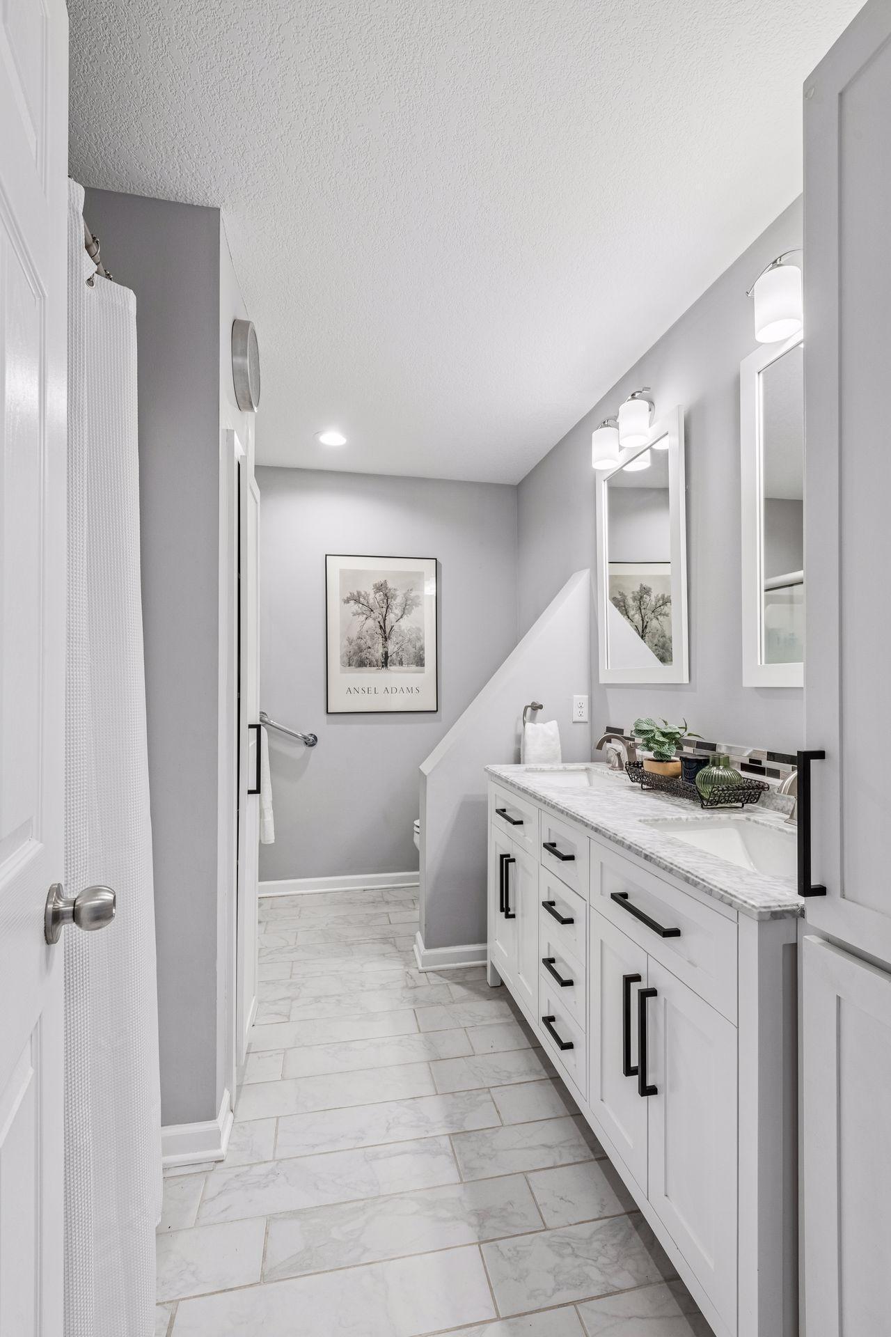 Upper level full bath with marble countertop, dual sinks, and separate tub/shower.