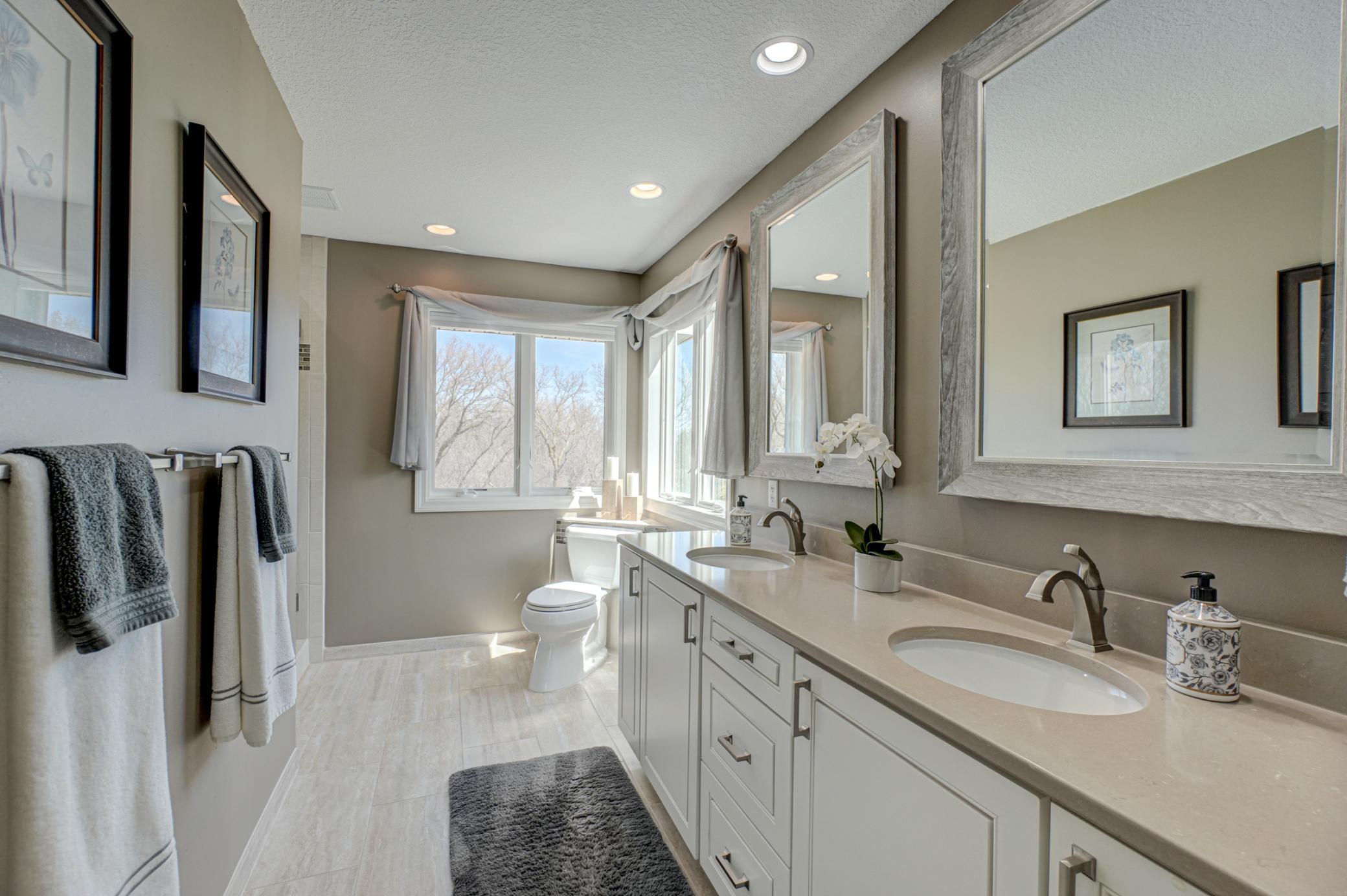 Sun-drenched and updated primary bathroom showcasing a double vanity