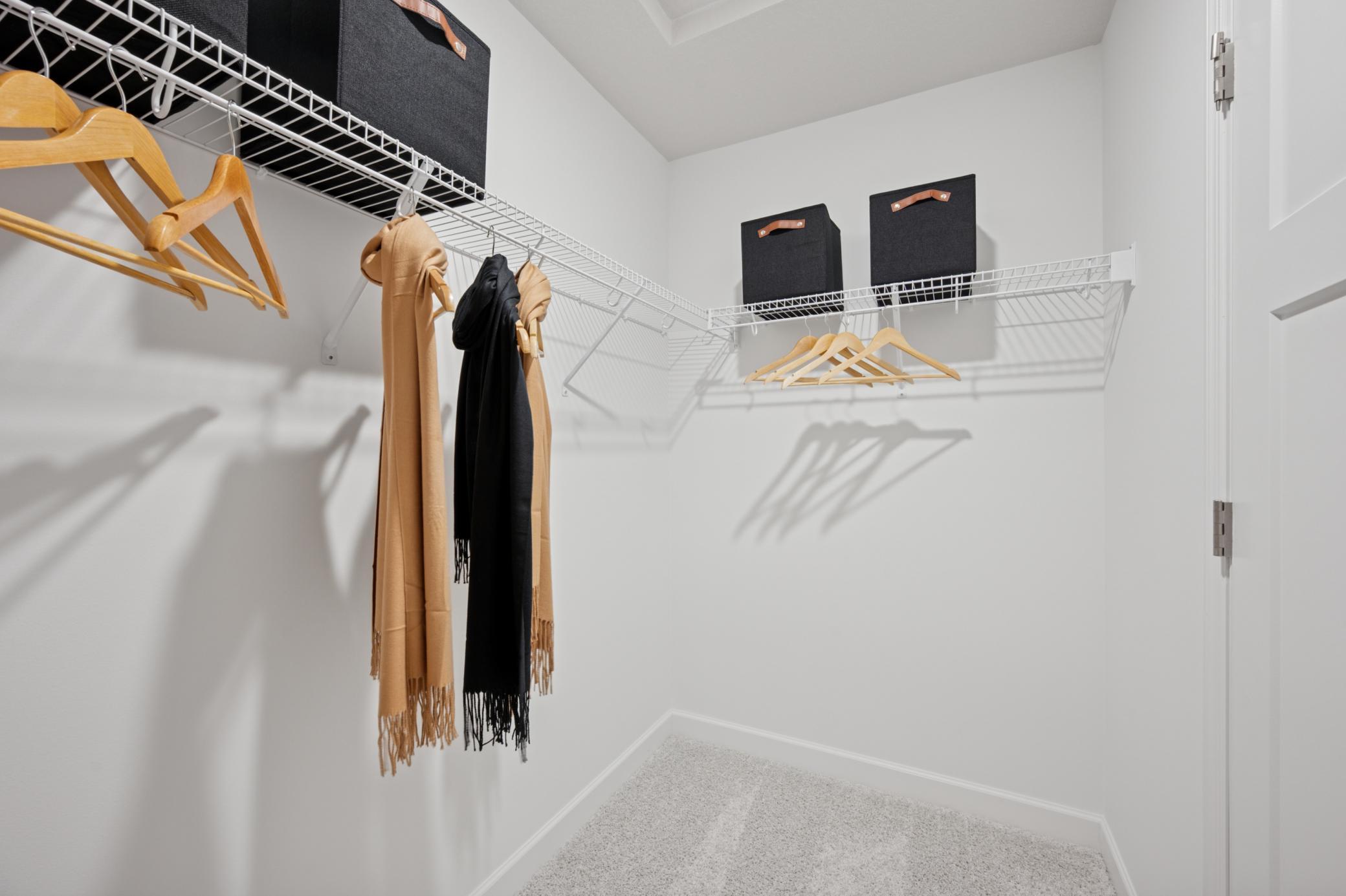 (Photo of a model home, finishes will vary) A large walk-in closet with mesh-wire shelving provides abundant room to store wardrobes, shoes, accessories and much more.
