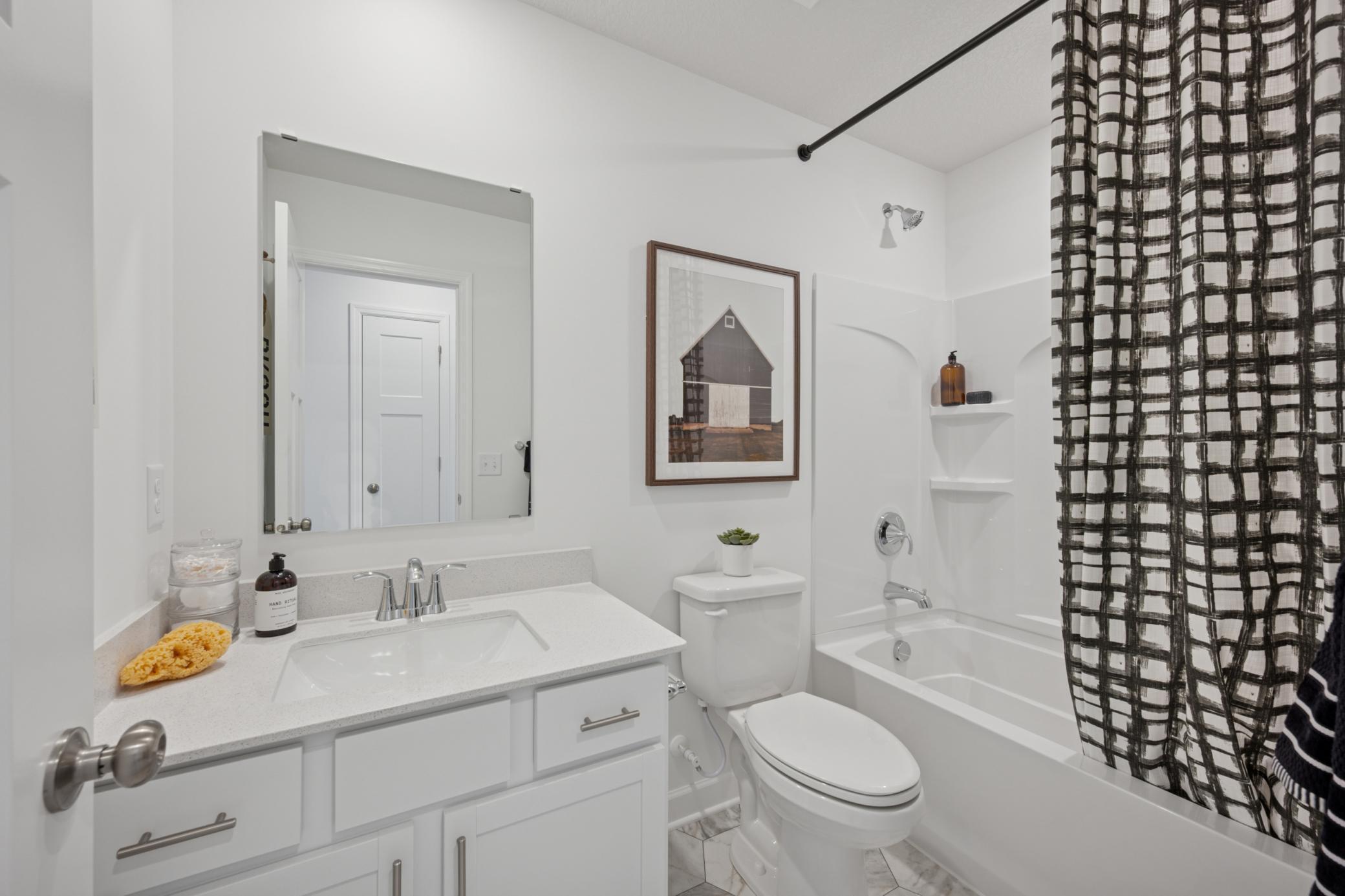 (Photo of a model home, finishes will vary) This full-sized bathroom is near the secondary bedrooms and features a single vanity and a shower-tub combination.