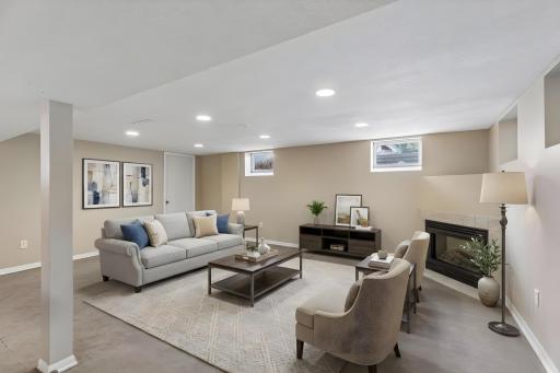 The spacious lower-level family room features a cozy gas fireplace, recessed lighting, and plenty of room for movie nights, entertaining, or everyday living. **Virtually staged to show design options.**