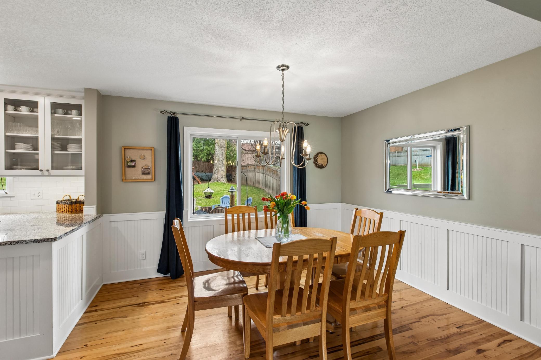 Dining Room with White Wainscoting. Hickory Hardwood flooring flows into the kitchen.