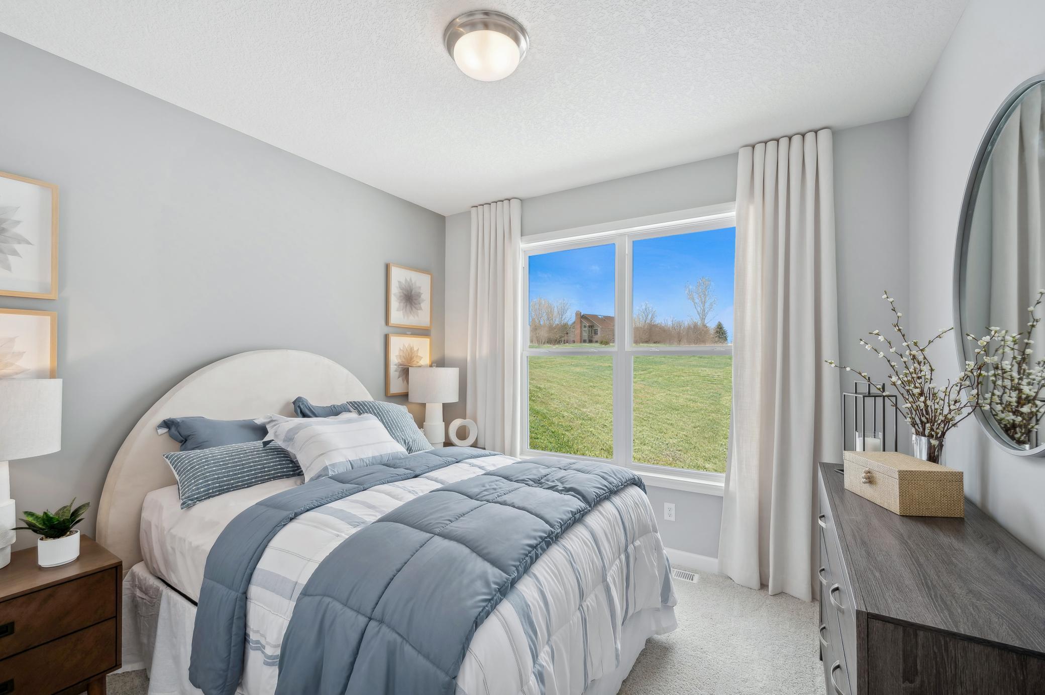 (Photo of a decorated model, actual homes finishes will vary) The main level bedroom.