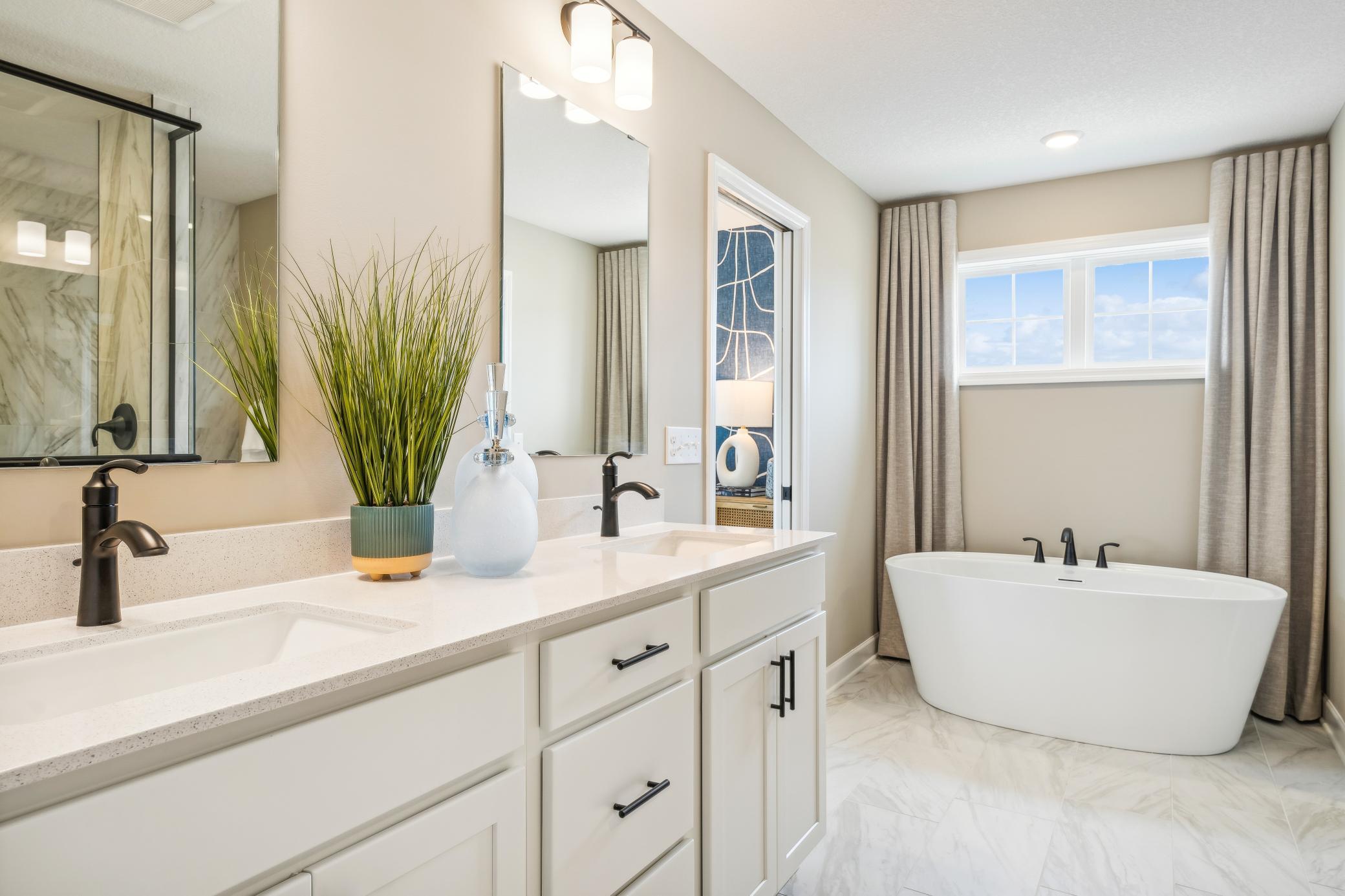 (Photo of a decorated model, actual homes finishes will vary) An extension of the primary bedroom, this private and spacious bath contains a double-vanity, a soaking tub, a serenity shower, and a walk-in closet.