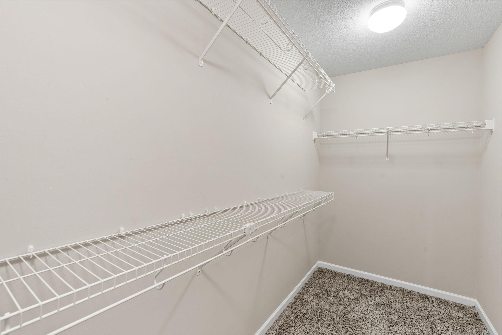 The first of two walk-in closets offers built-in wire shelving layout maximized for clothing, shoes, and seasonal storage.