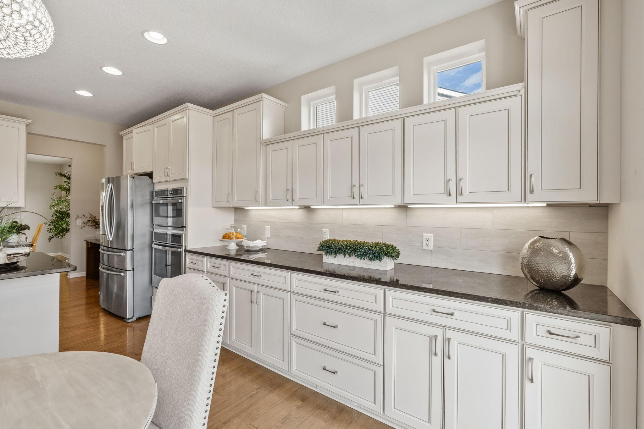 A massive wall of crisp white cabinetry and dark granite countertops offers incredible storage space and serving room for large gatherings.