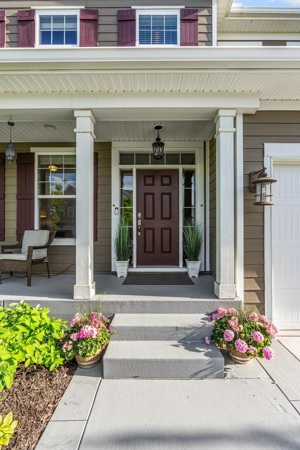 The rich, deep-toned front door is flanked by elegant sidelights and transom windows, bringing a touch of symmetry and natural light right to your doorstep.