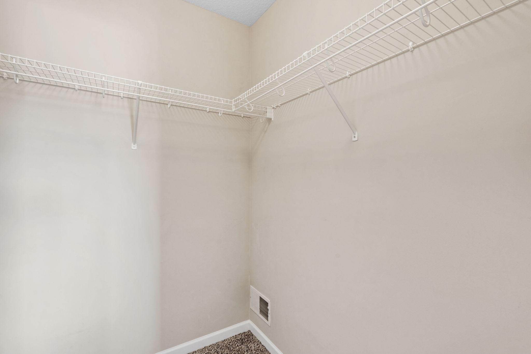A dedicated walk-in closet within the secondary bedroom features wrap-around wire shelving for easy wardrobe organization.
