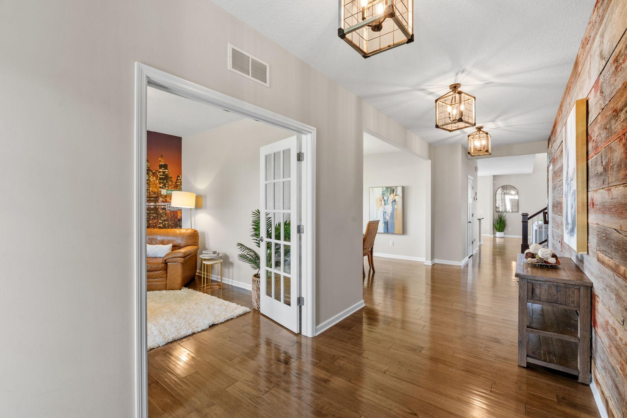 Elegant French doors open from the main hallway into a private front room, ideal for a quiet den, library, or home office setup.